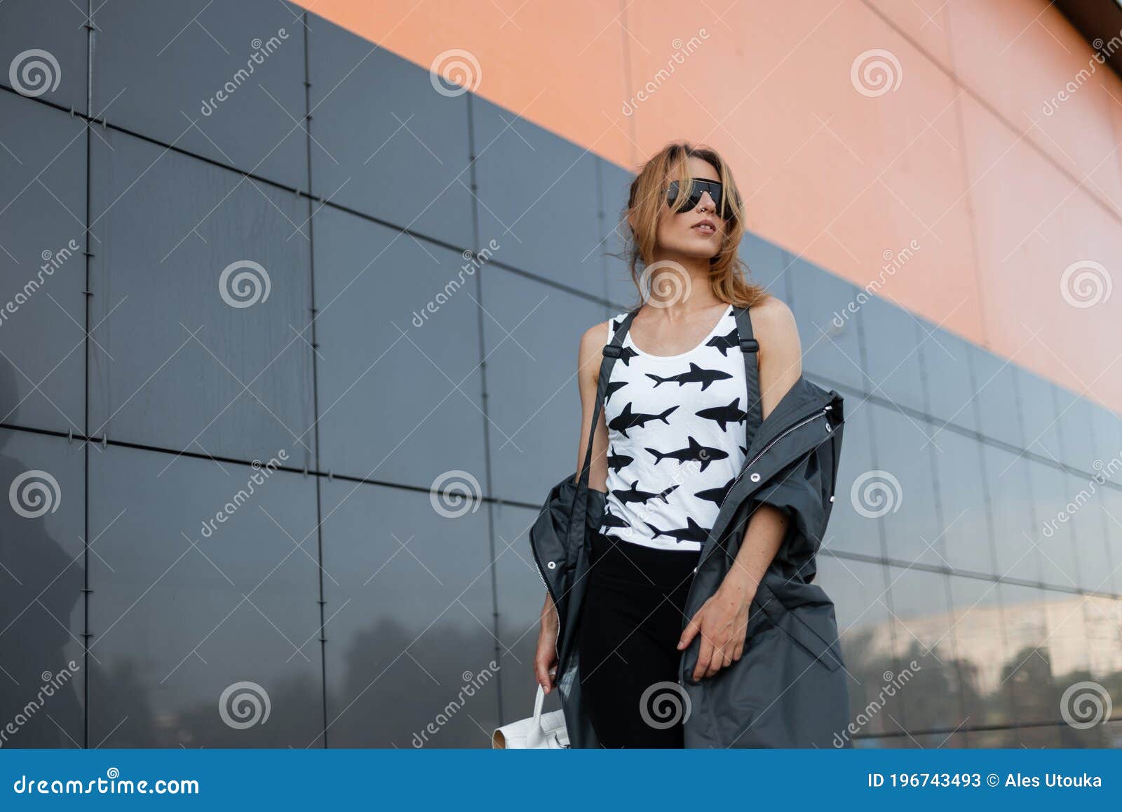 Mujer Hipster Urbana Atractiva Con Ropa De Diseño Y Gafas Sol Vintage Con Una Mochila Posa En Una Ciudad Cercana a Un Gr Imagen archivo - Imagen de atractivo,