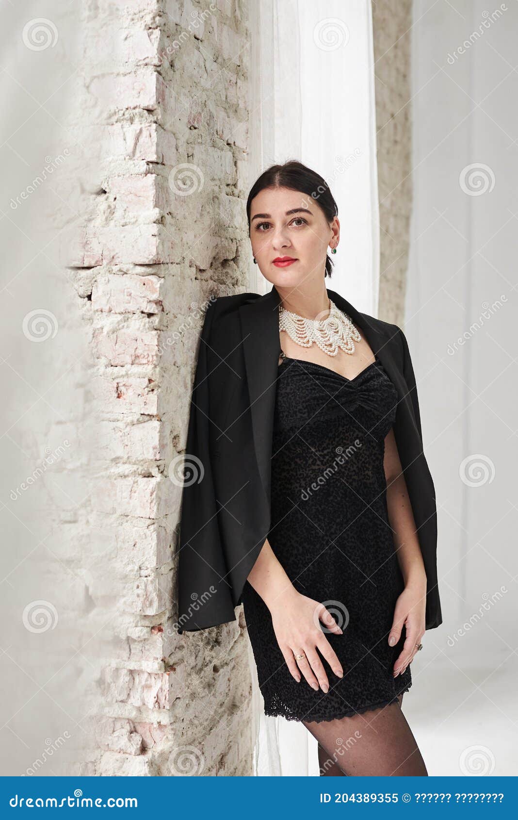 Joven Morena Que Lleva El Pequeño Vestido Negro Corto Y La Chaqueta Inteligente Que Hacen Una Pausa En La De Ladrillo Imagen de archivo - Imagen de hermoso: 204389355