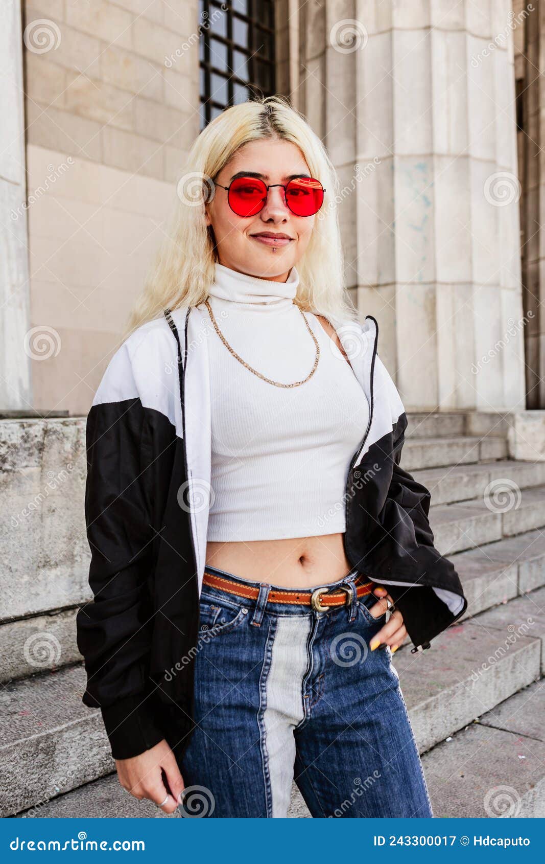 Latina Joven Y Sonriente Moderna Con Gafas Rojas, Camiseta Blanca Y Jeans En Las Escaleras De La Universidad. Retrato Vertic Imagen de archivo - de inconformista, 243300017