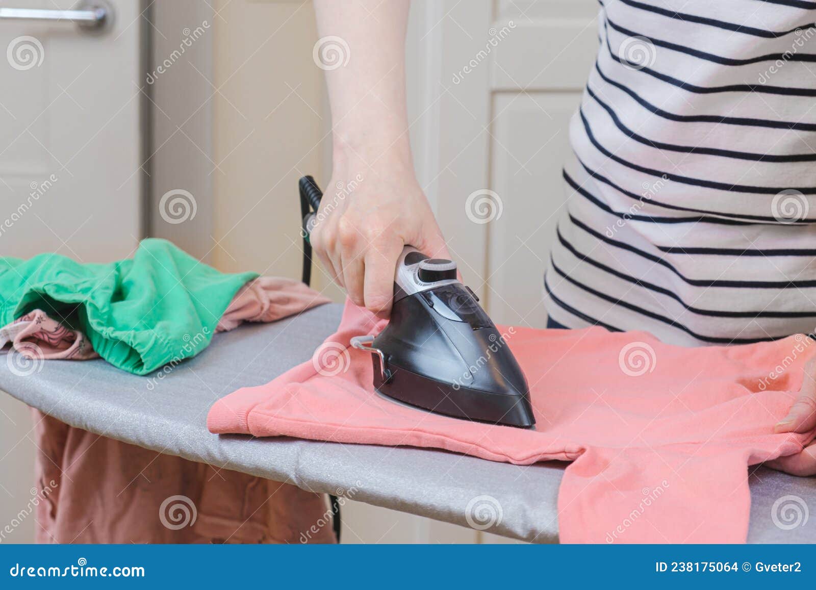 Mujer Planchando Ropa Limpia Para Bebé En Una Tabla De Planchar Con Una Pequeña  Plancha Foto de archivo - Imagen de higiene, lino: 238175064