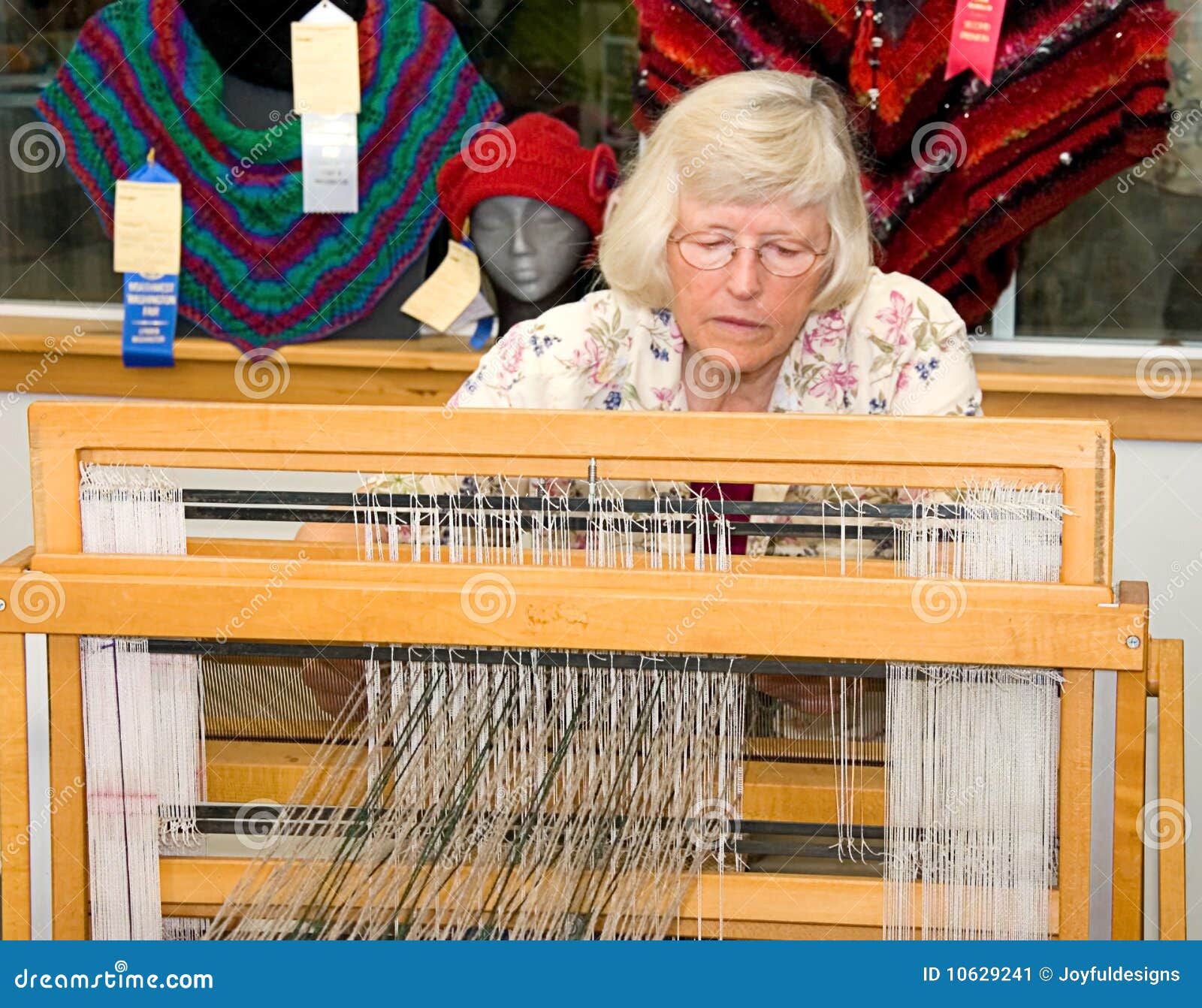 Mujer que demuestra tejer en telar. LYNDEN, WA - 19 de agosto de 2009 - gama de Jane está demostrando en un acontecimiento vivo en la feria de Lynden recientemente el uso de un telar de la materia textil de esta mujer envejecida mayor. Los Temps golpearon recientemente en los dígitos triples.