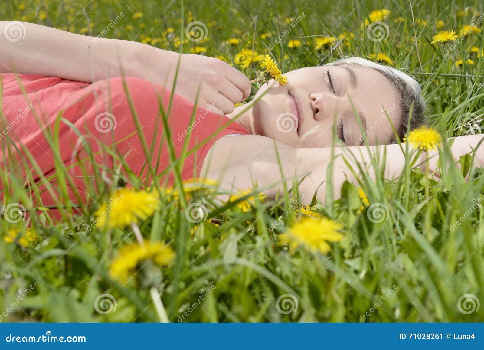 Mujer que miente en prado de la flor. Mujer rubia joven que miente en prado de la flor