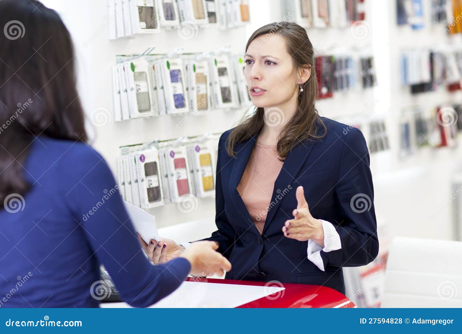 Mujer que se queja en un almacén de la electrónica. Mujeres hermosas que se quejan en un almacén con los teléfonos elegantes