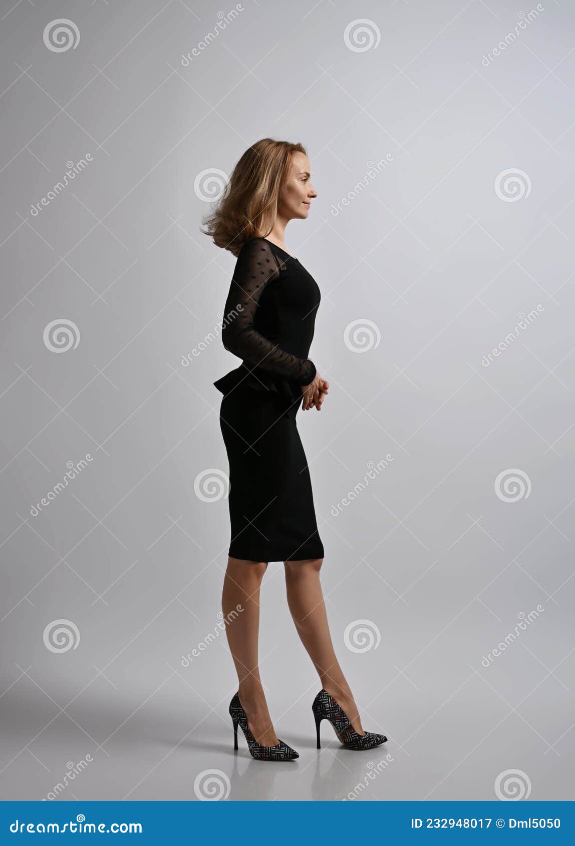 Mujer Rubia Delgada Trabajadora De Oficina Con Vestido Negro Formal Y Zapatos Tacón Alto Se Para De Lado a La Cámara Imagen de - Imagen de manera, semitransparente: 232948017