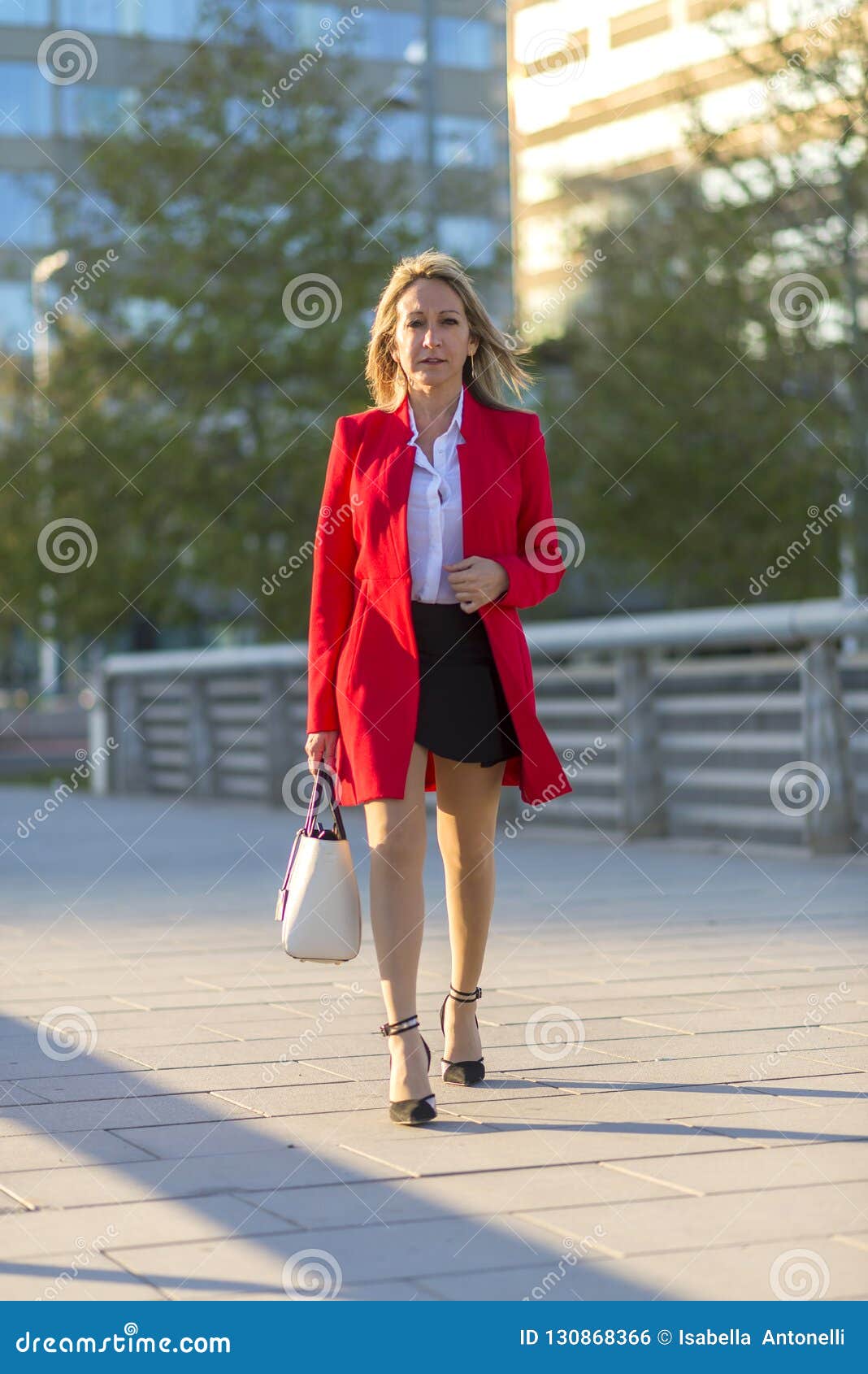 Secreto usted está Ingenioso Mujer Rubia Que Lleva La Chaqueta Roja Y El Bolso Blanco Que Caminan En  Foto de archivo - Imagen de edificios, rojo: 130868366