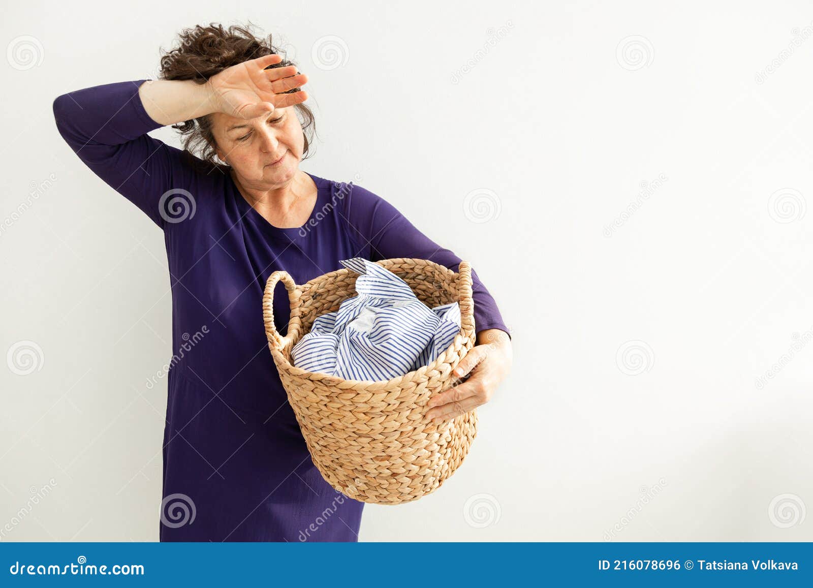 Mujer sosteniendo una cesta de mimbre con ropa limpia