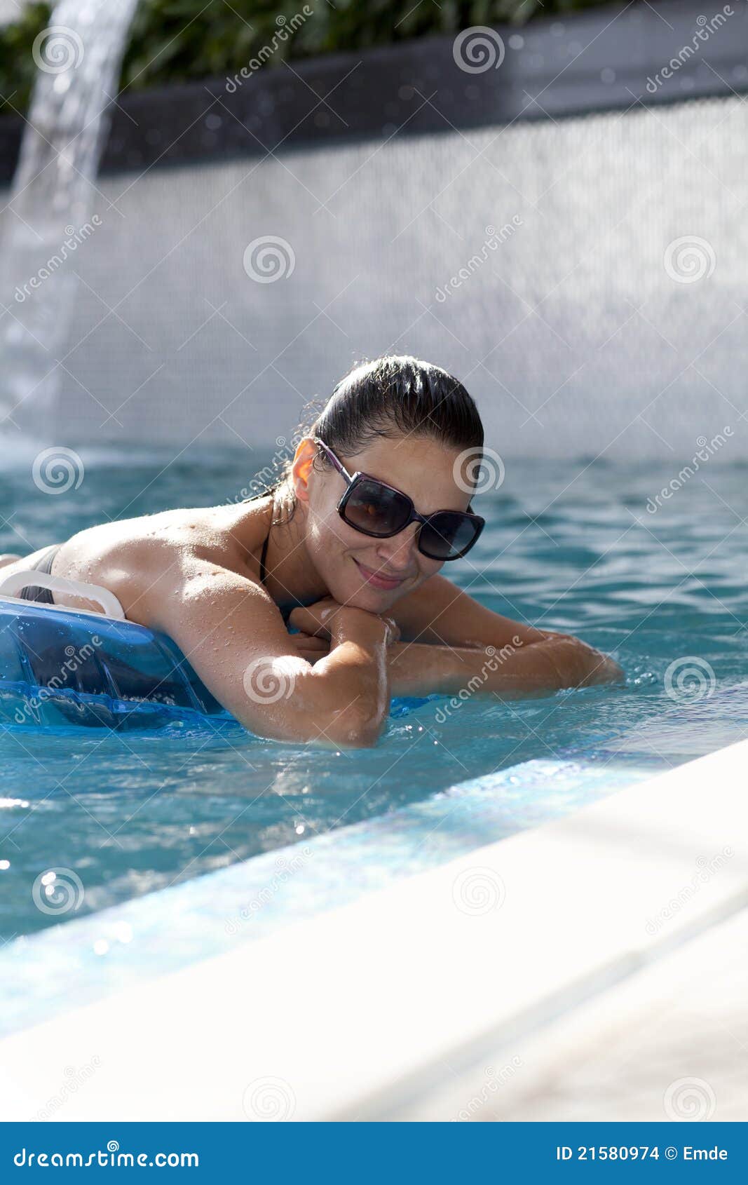 Mujer sonriente que flota en piscina. Hembra sonriente en el borde de una piscina