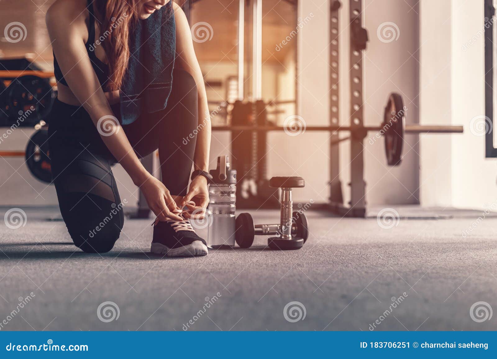 Mujer atlética atando sus zapatillas sentadas en el piso del