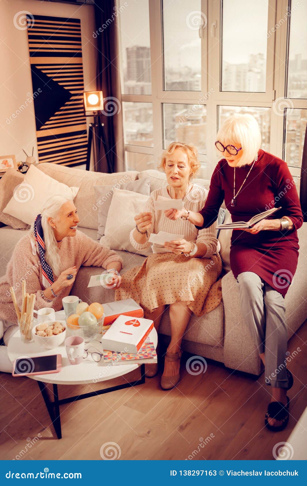 Nuestras últimas mujeres mayores agradables que miran las fotos viejas mientras que recuerda su pasado