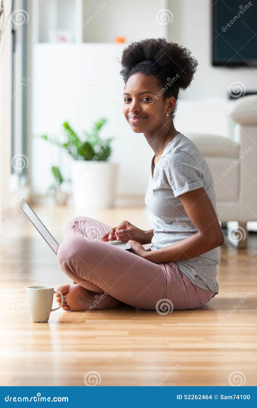 Mulher afro-americano que usa um portátil em sua sala de visitas - preto