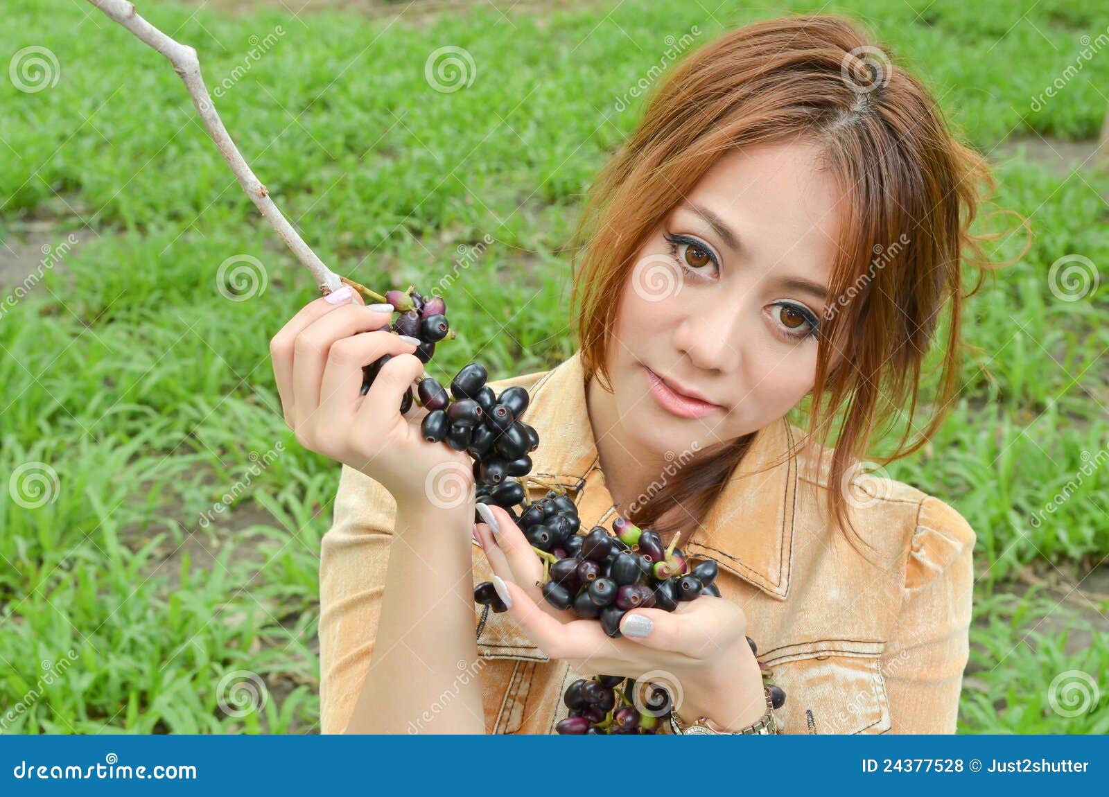 A mulher bonita come a fruta no parque. Fruta bonita da terra arrendada da mulher no parque