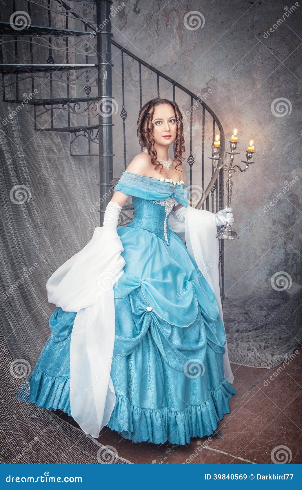 Mulher bonita no vestido medieval azul com candelabro. Jovem mulher bonita no vestido medieval azul longo com candelabro