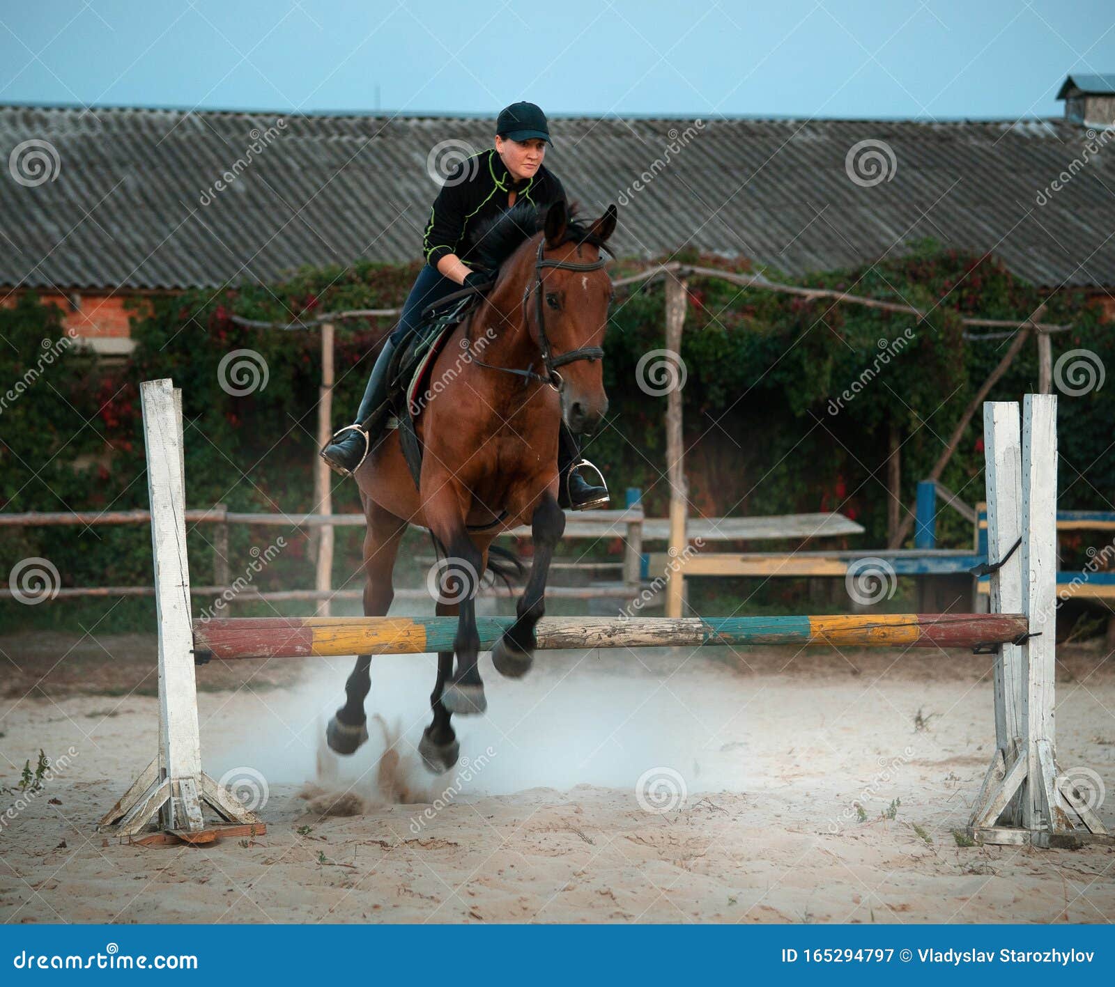 Uma pessoa andando a cavalo está pulando uma cerca.