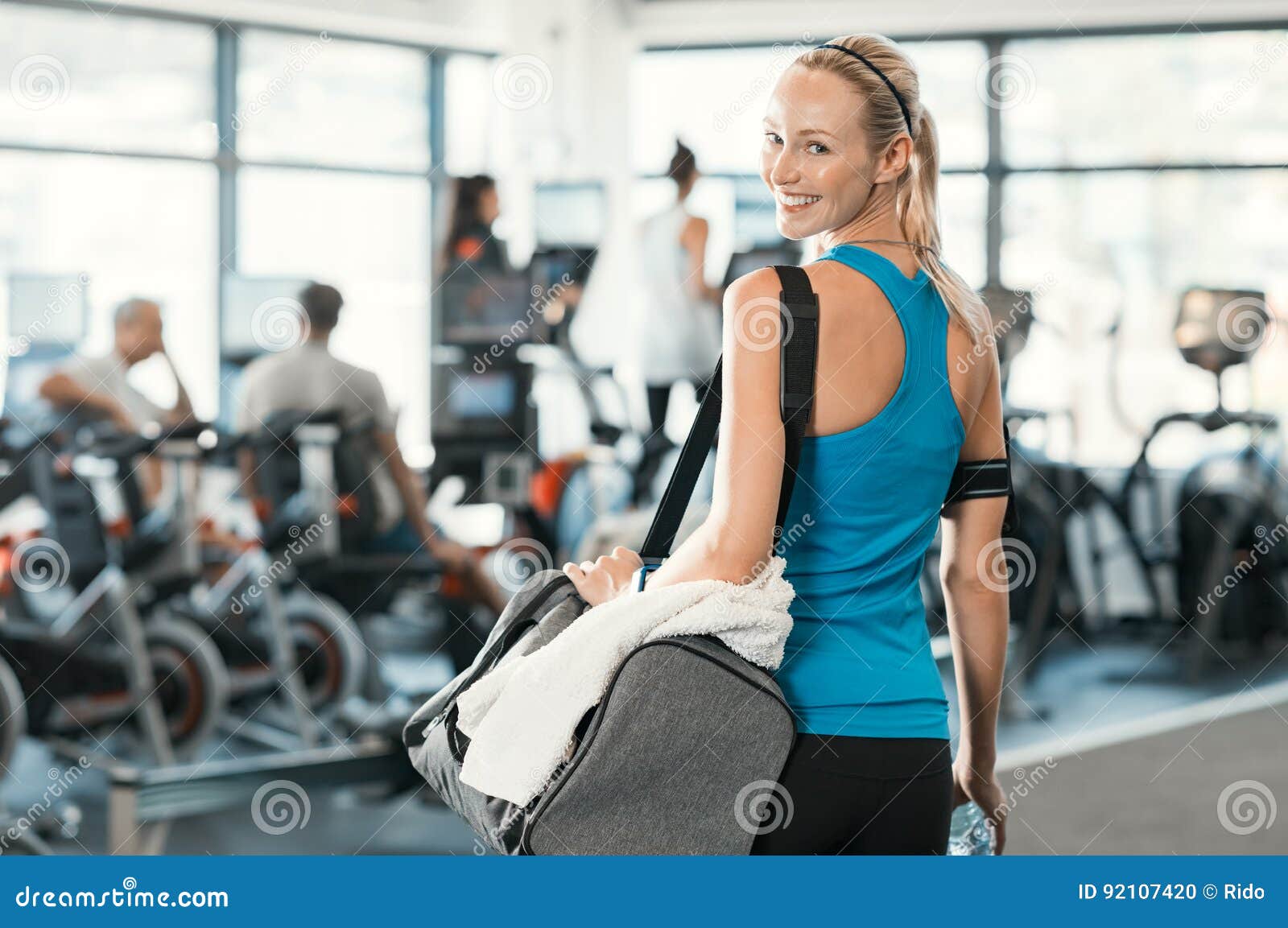 Mulher com saco do gym. Mulher apta que guarda o saco do gym em um centro de aptidão Mulher loura bonita pronta para começar seu treinamento Retrato da mulher energética que olha pronto para a reprodução fotográfica para a inscrição nova no gym