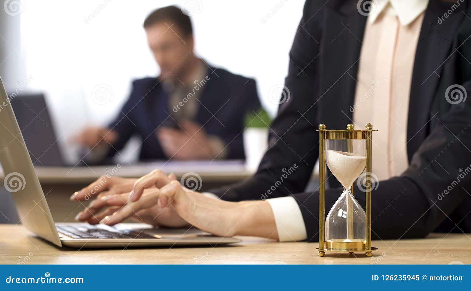 Mulher de negócios que trabalha no computador, ampulheta que goteja, antecipação do resultado, foto conservada em estoque
