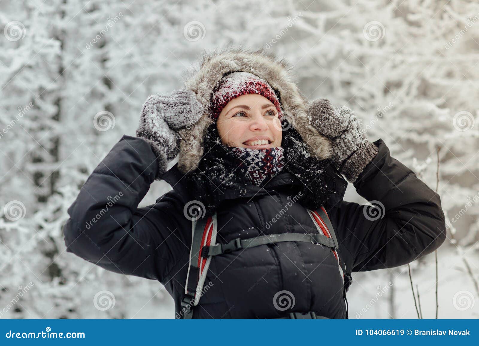 A mulher de sorriso vestiu a terra arrendada morna sua capa com luvas nevado. Turista fêmea feliz que trekking e que admira as árvores cobertas na neve