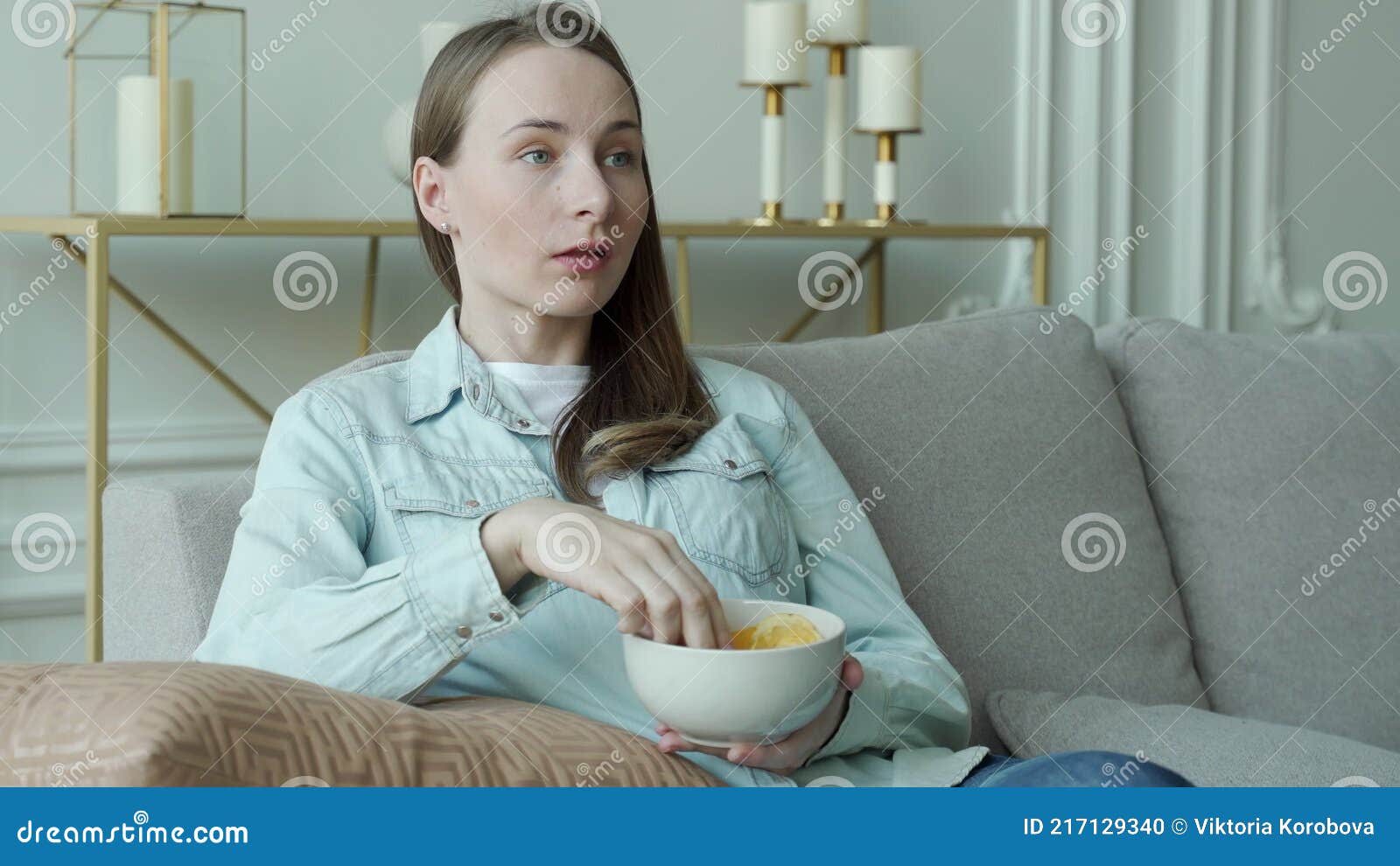 Mulher jovem comendo batata frita assistindo filme na mesa azul