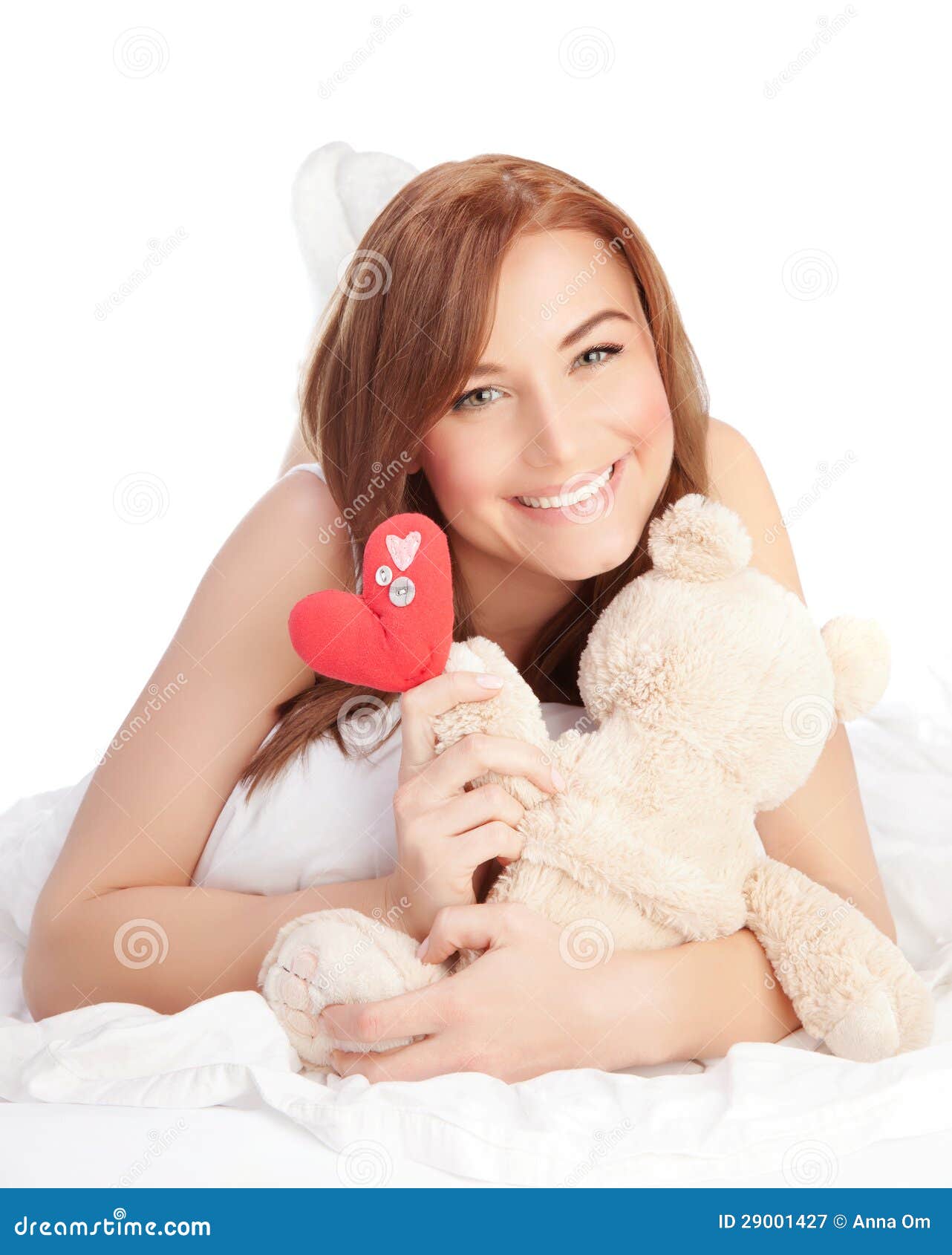 Mulher no amor. A imagem da mulher feliz que estabelecem na cama, a menina que apreciam o urso atual, macio romântico e a coração-forma handmade vermelha brincam como presente para o feriado do dia de Valentim, isolado no fundo branco, conceito do amor