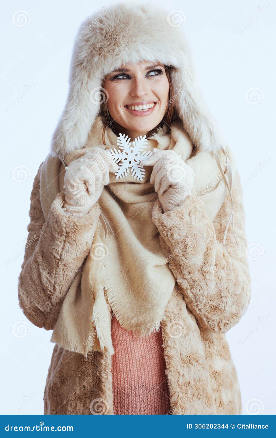 Mulher sorridente em casaco de inverno e chapéu de pele em branco. Sorridente mulher moderna de 40 anos em casaco de inverno e pelo que se isolou em fundo branco em luvas brancas com floco de neve