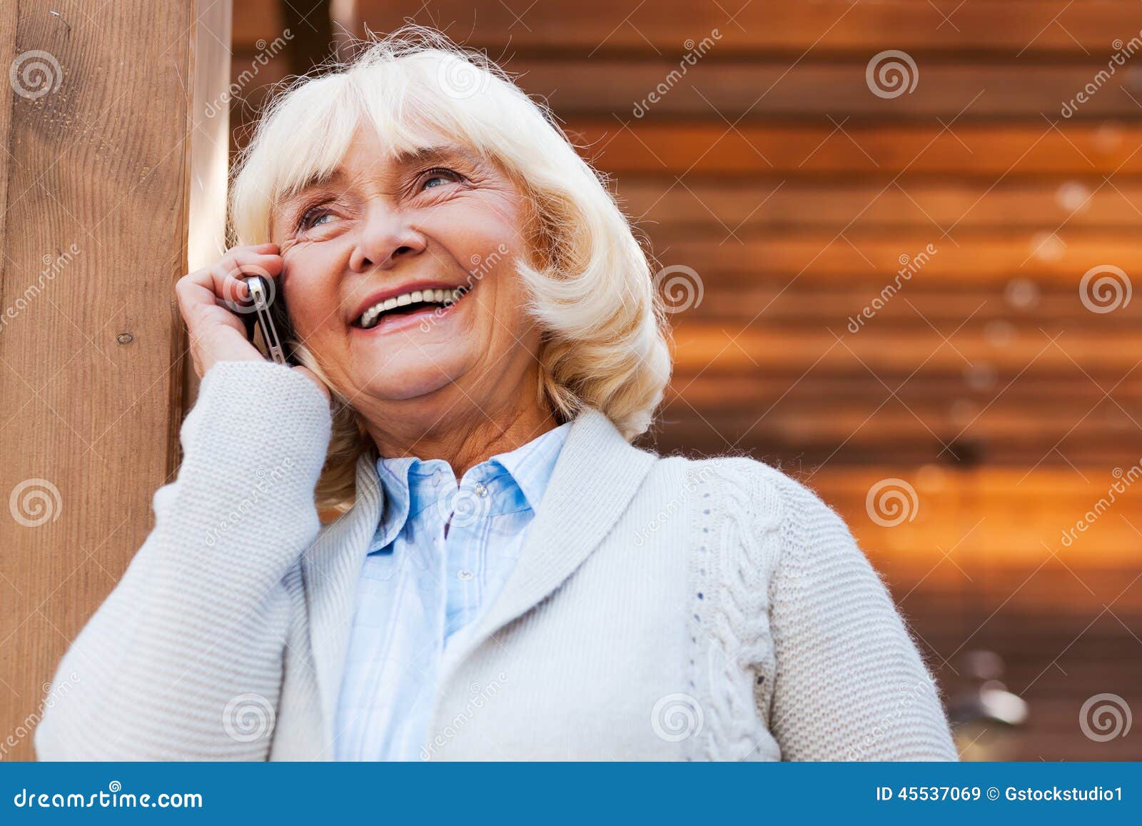 Mulher sênior no telefone. Mulher superior feliz que fala no telefone celular e que sorri ao estar fora