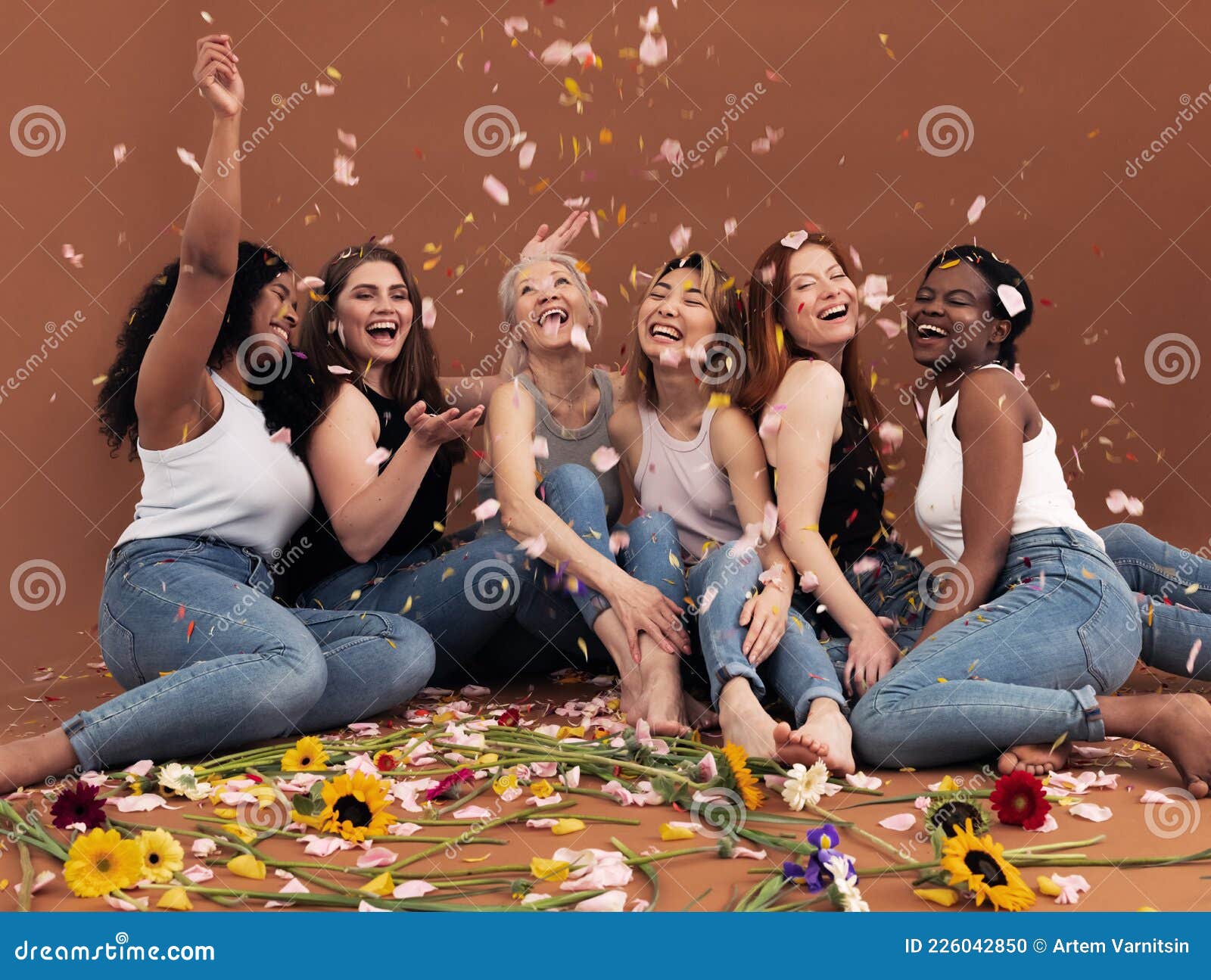 multi ethnic group of happy women sitting under falling petals