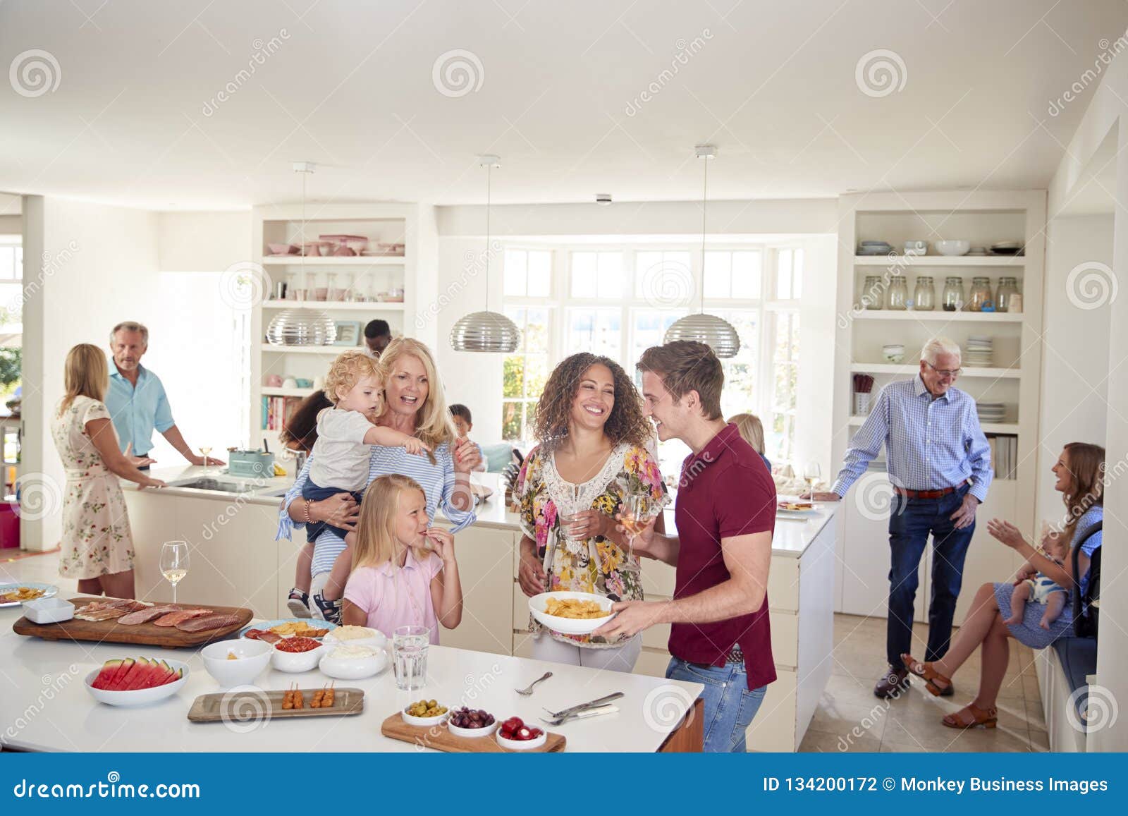 multi-generation family and friends gathering in kitchen for celebration party