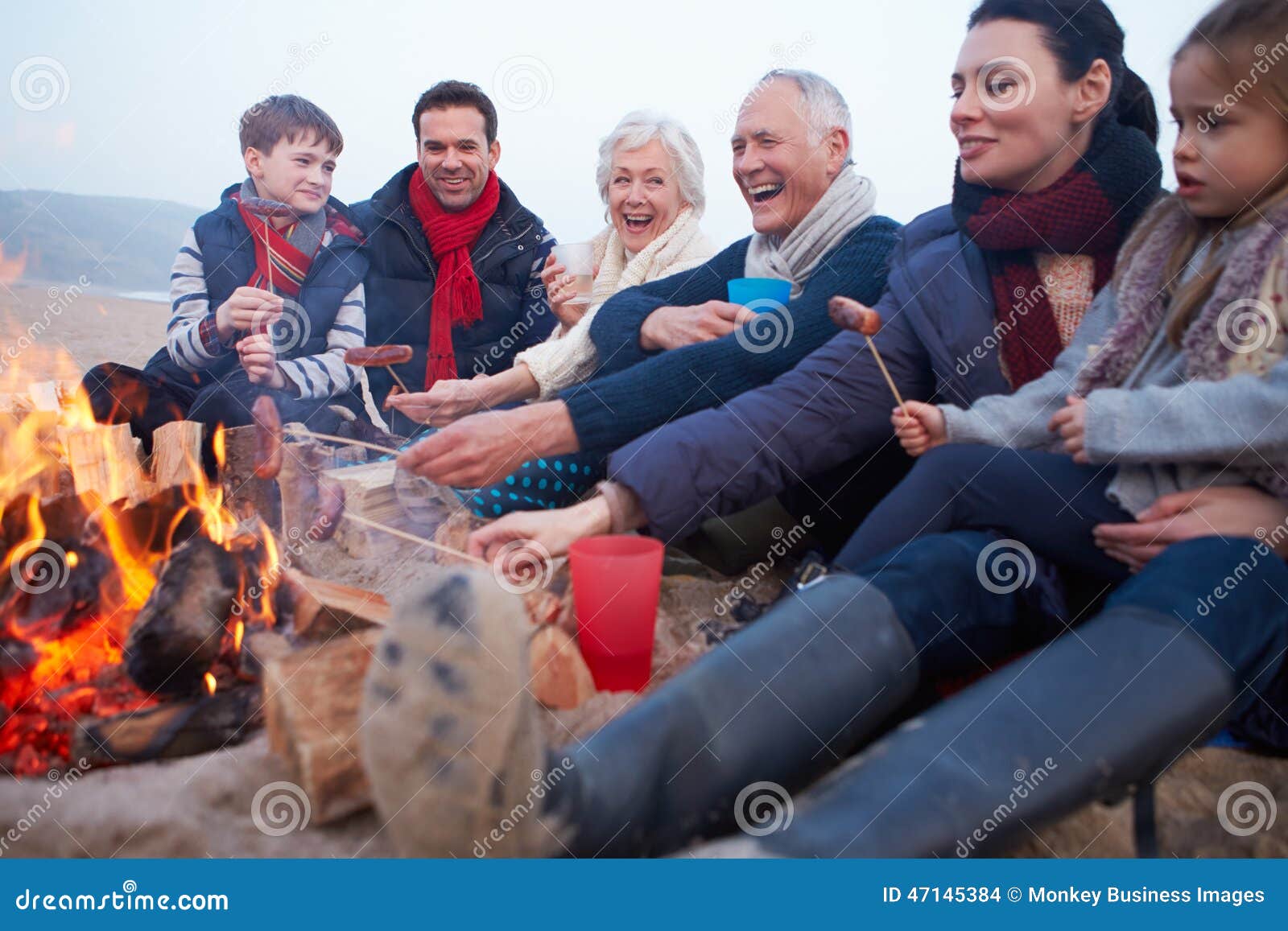 multi generation family having barbeque on winter beach
