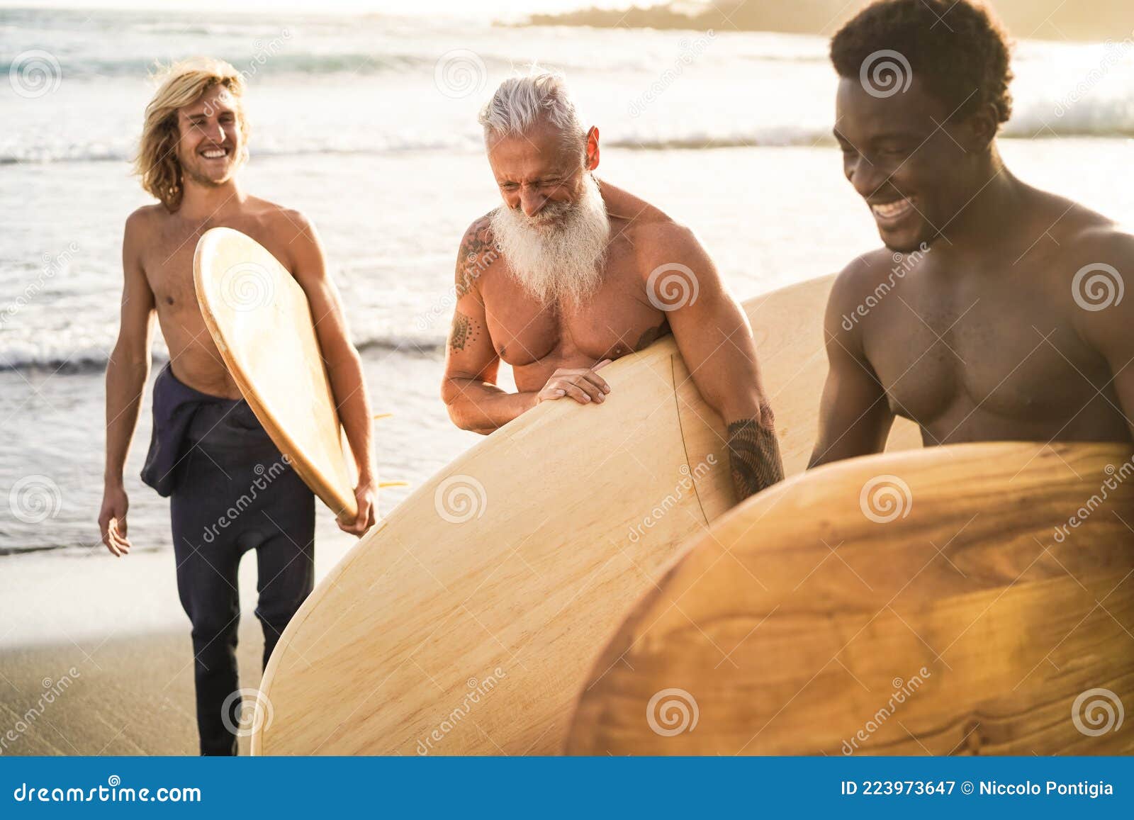 multi generational surfer friends having fun on the beach after surf session - focus on senior man face