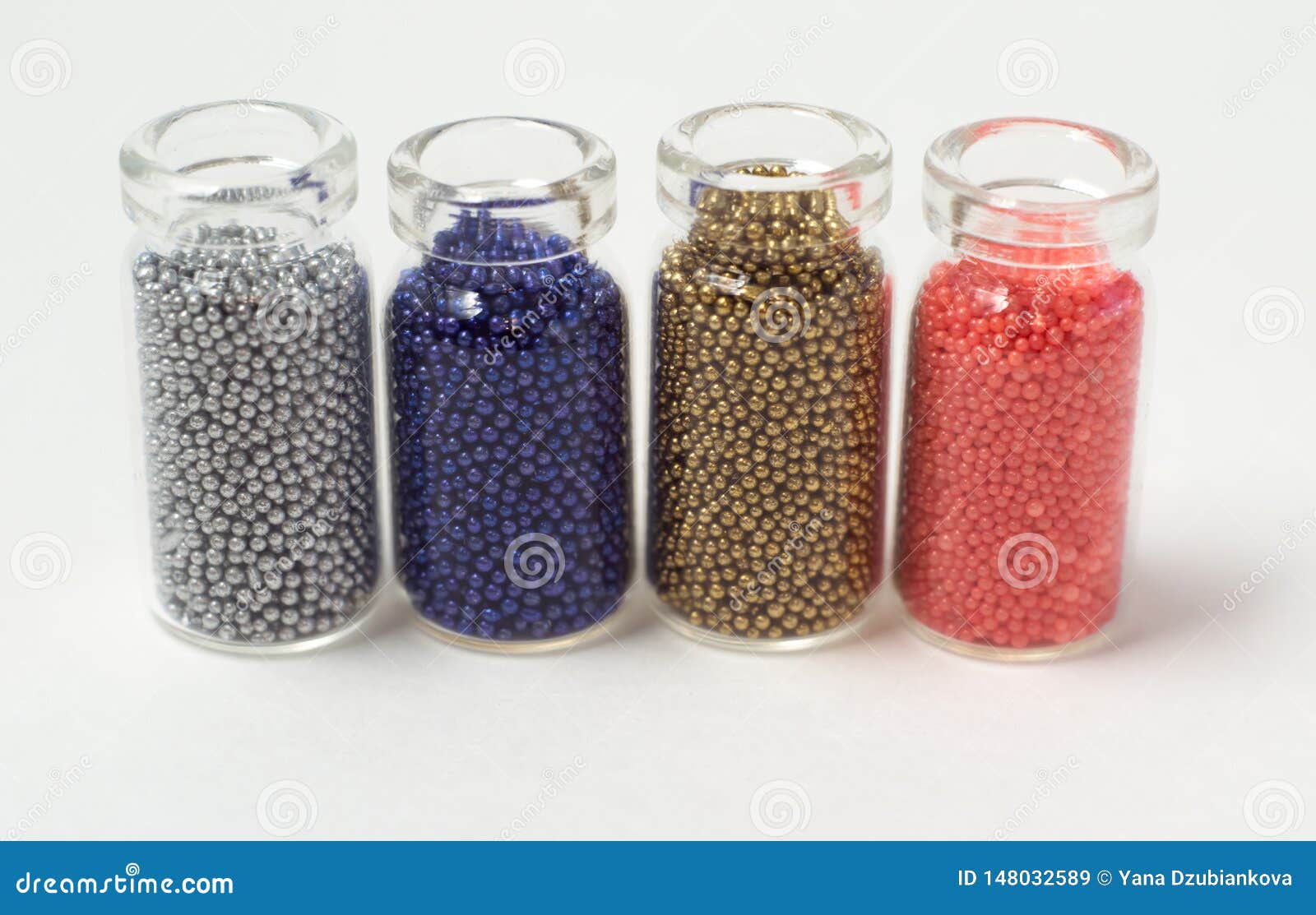 Multicolored Beads in Glass Jars. Beads are Poured on a White