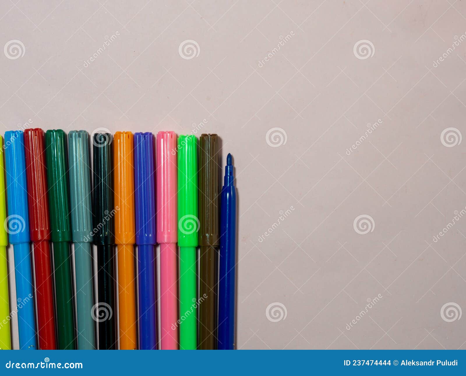 multicolored markers on a pink background. creative atmosphere. one marker without cap