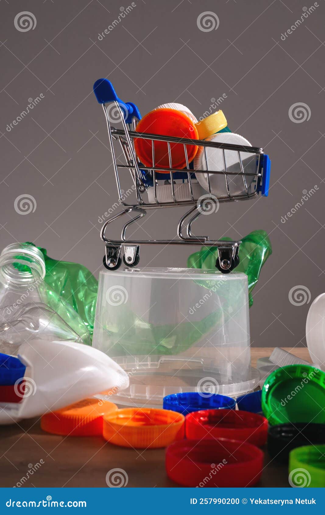 Multicolored Plastic Bottle Caps and Waste in Shopping Trolley Stock
