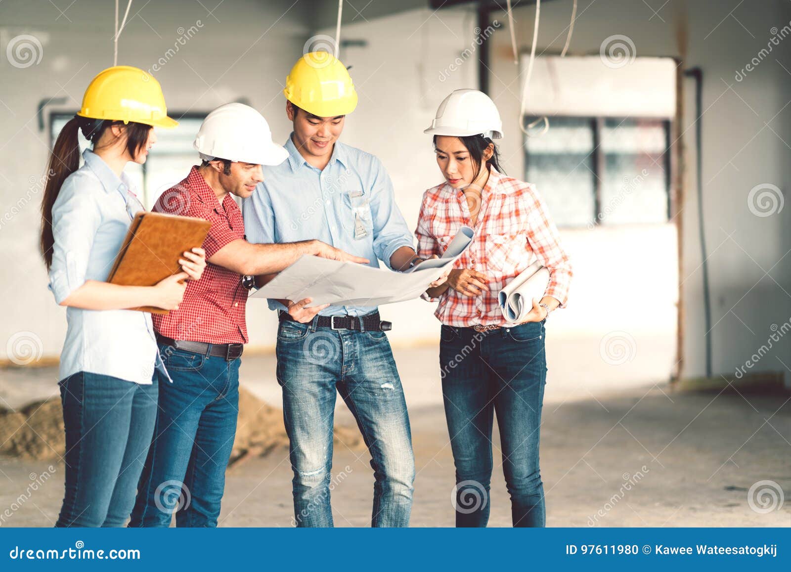 multiethnic diverse group of engineers or business partners at construction site, working together on building`s blueprint