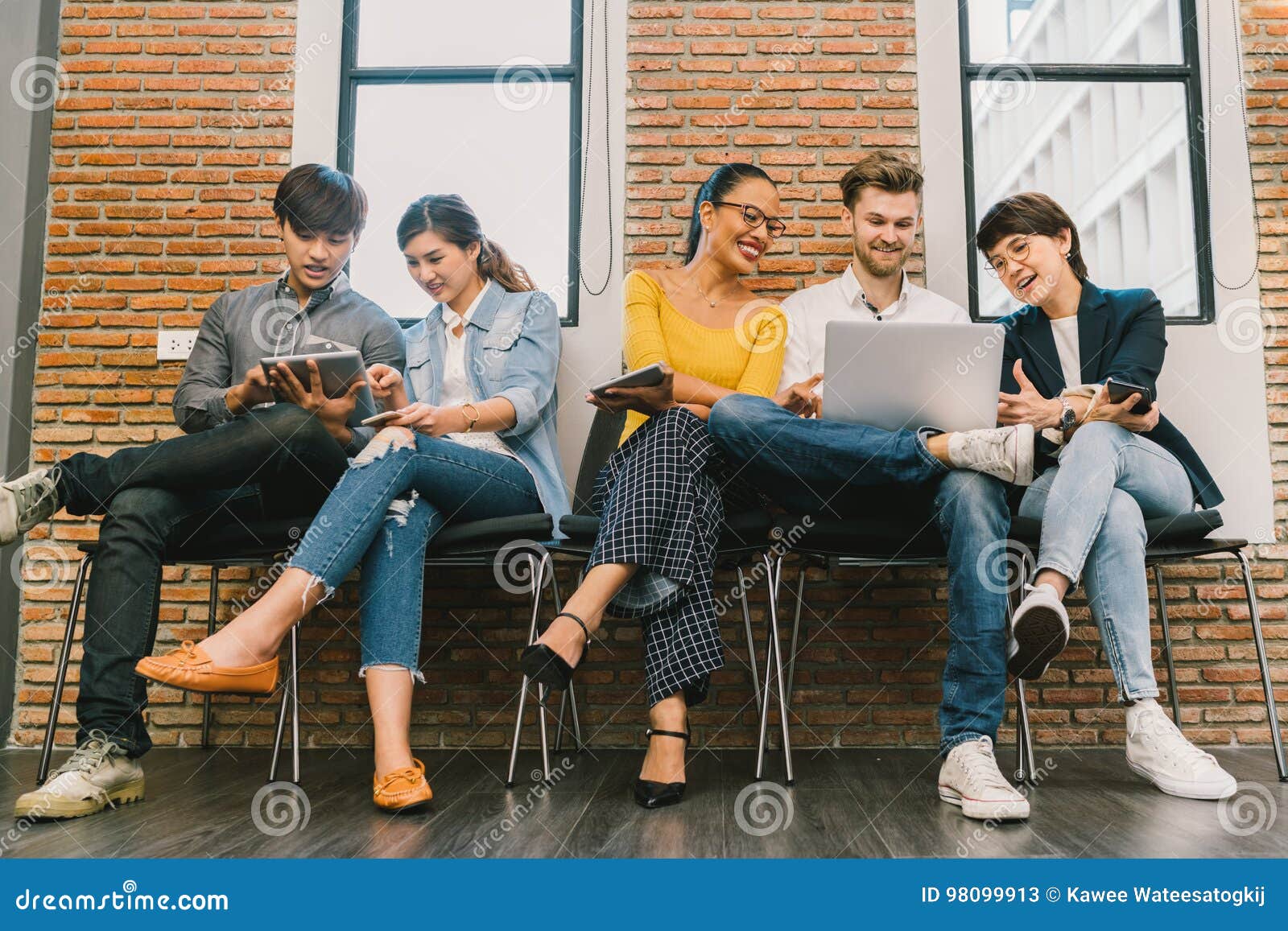 multiethnic diverse group of young and adult people using smartphone, laptop computer, digital tablet together