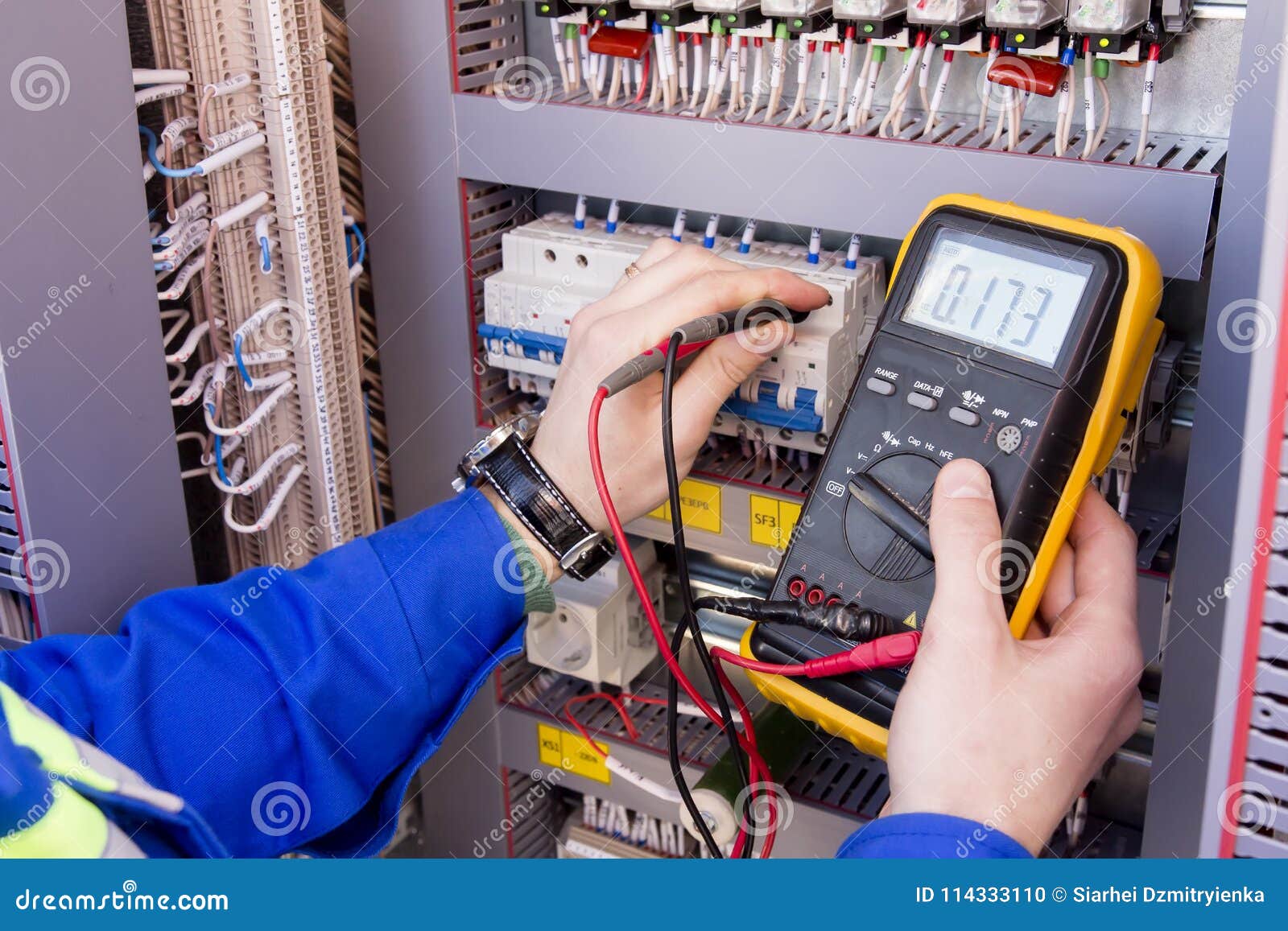multimeter is in hands of engineer in electrical cabinet. adjustment of automated control system for industrial equipment