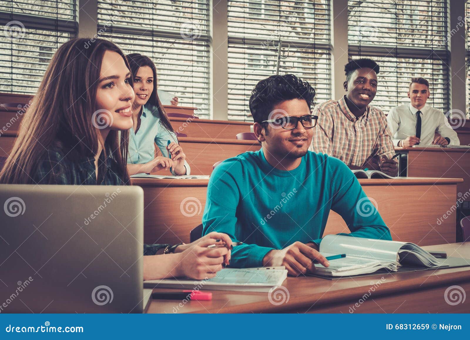 multinational group of cheerful students taking an active part in a lesson while sitting in a lecture hall.