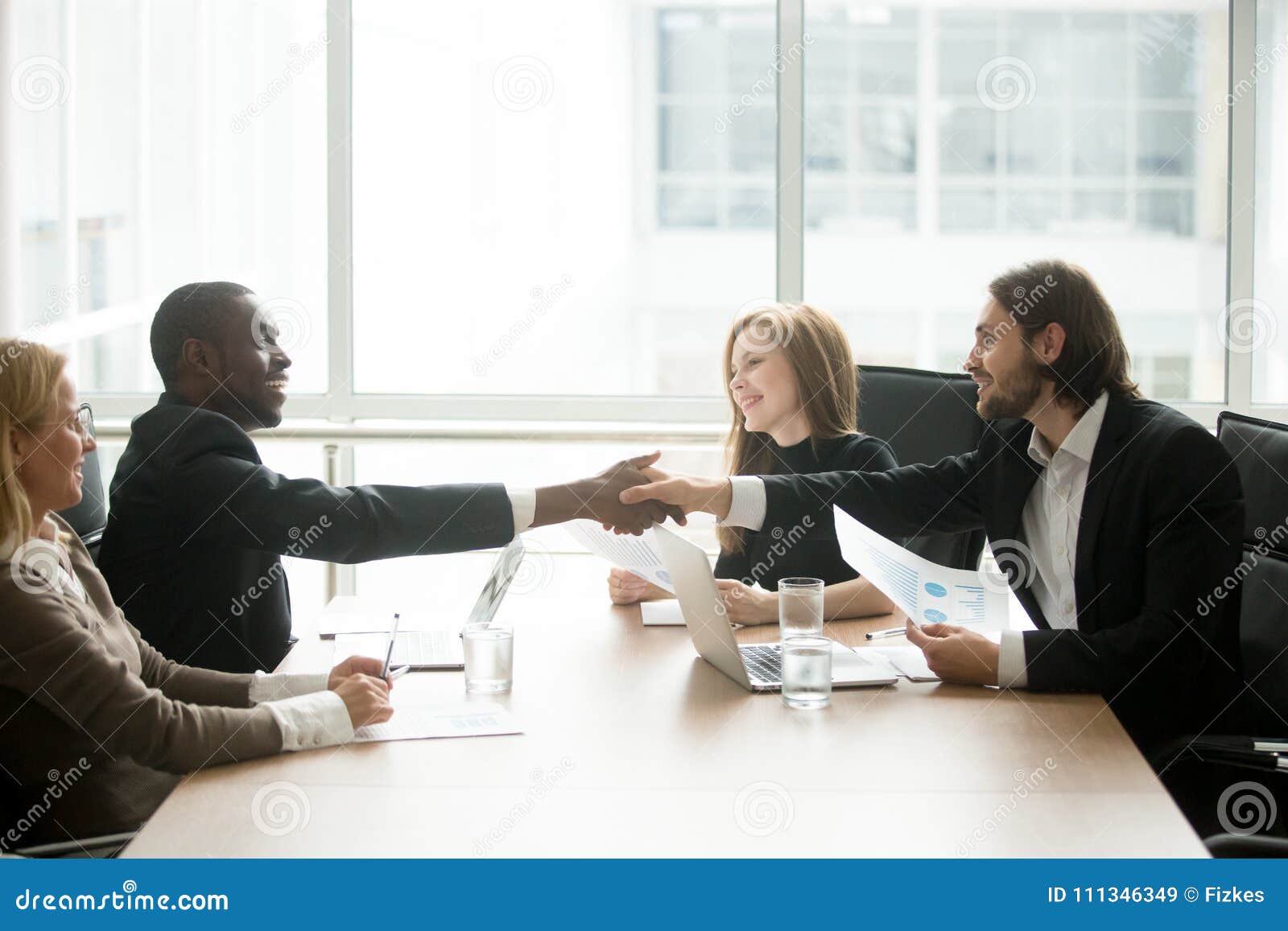 multiracial businessmen in suits handshaking at executive team o