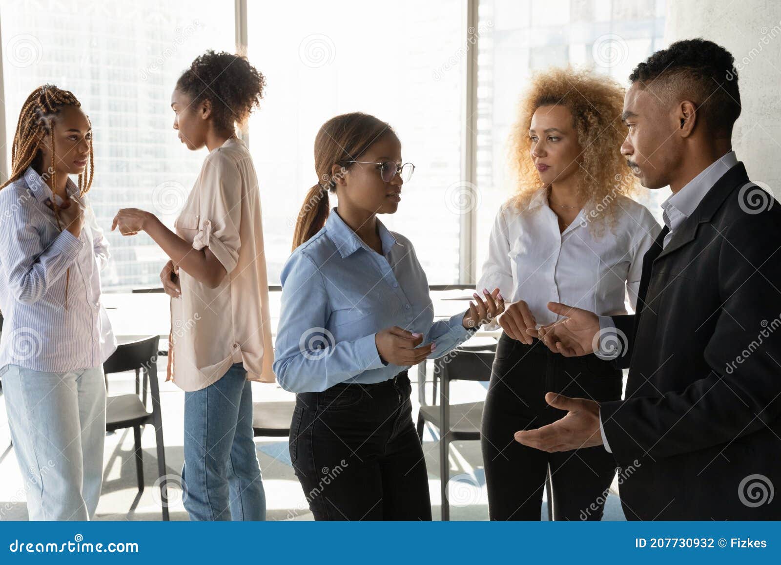 Multiracial Colleagues Talk In Groups In Office Together Stock Photo