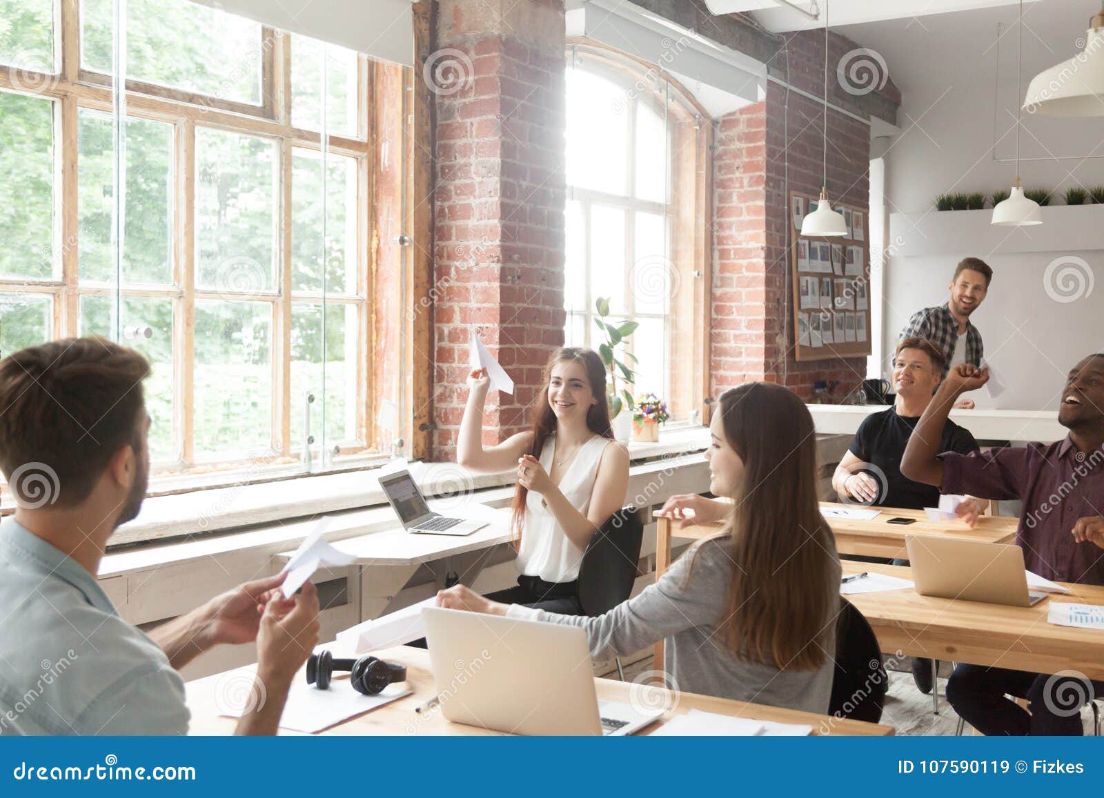 multiracial corporate team launching paper planes in coworking o