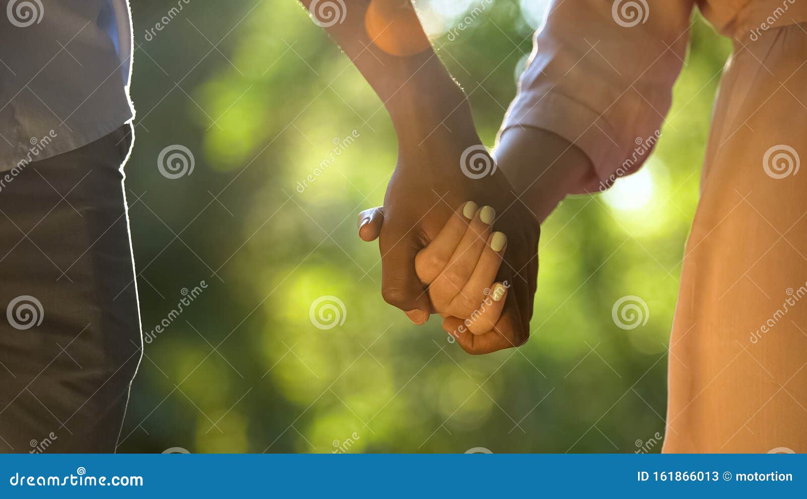multiracial couple holding hands at sunny park, romantic and intimacy, close-up