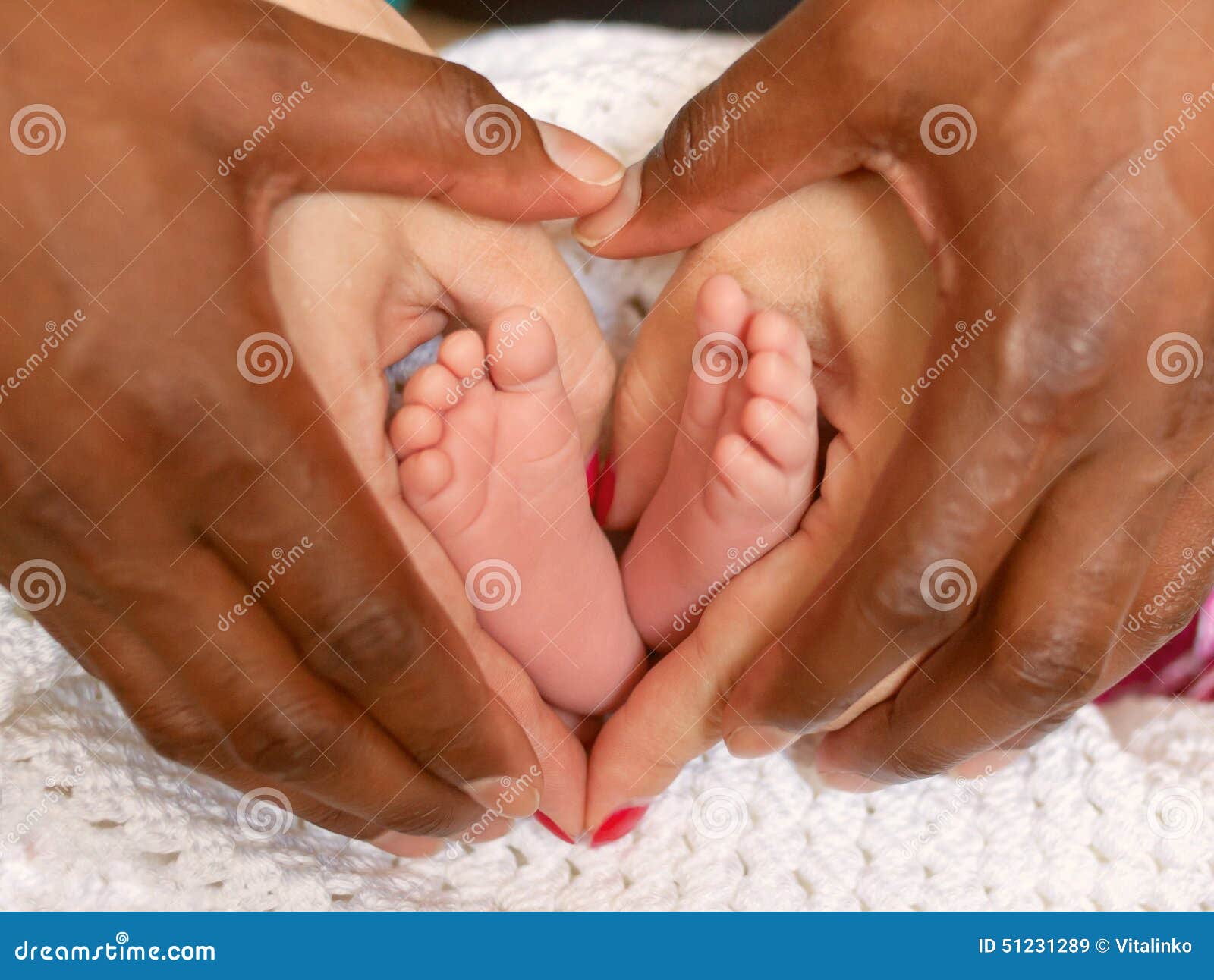 multiracial family concept. hands holding mulatto baby feet .