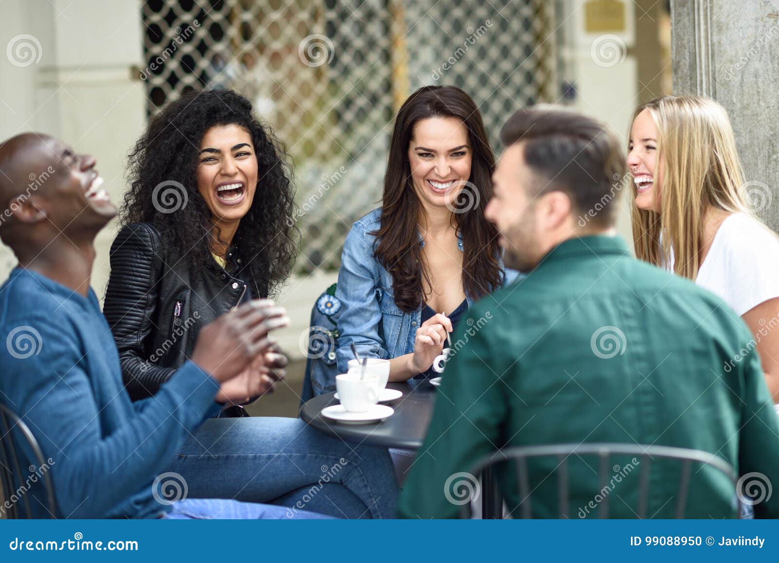 multiracial group of five friends having a coffee together