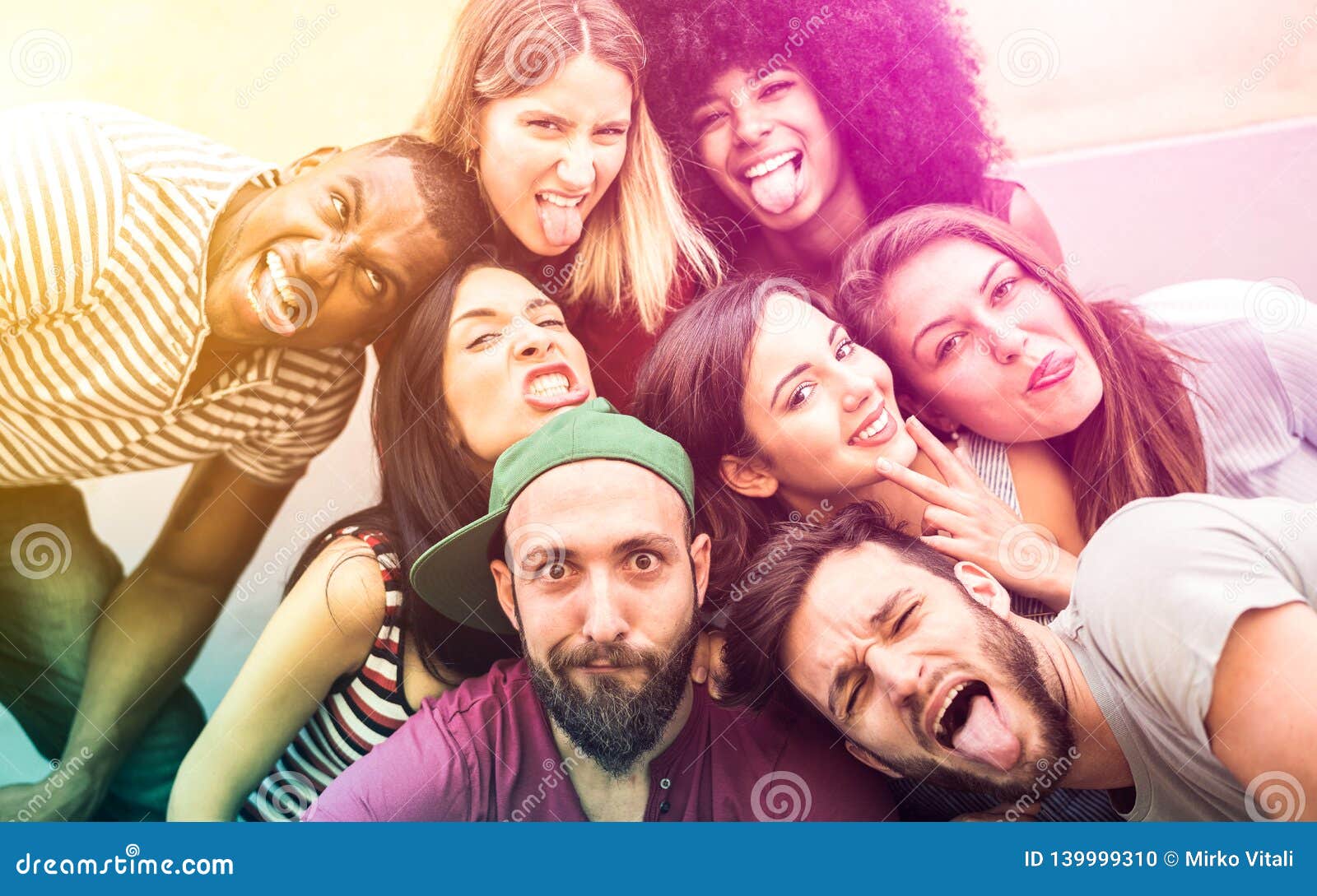 multiracial millenial friends taking selfie with funny faces - happy youth friendship concept against racism