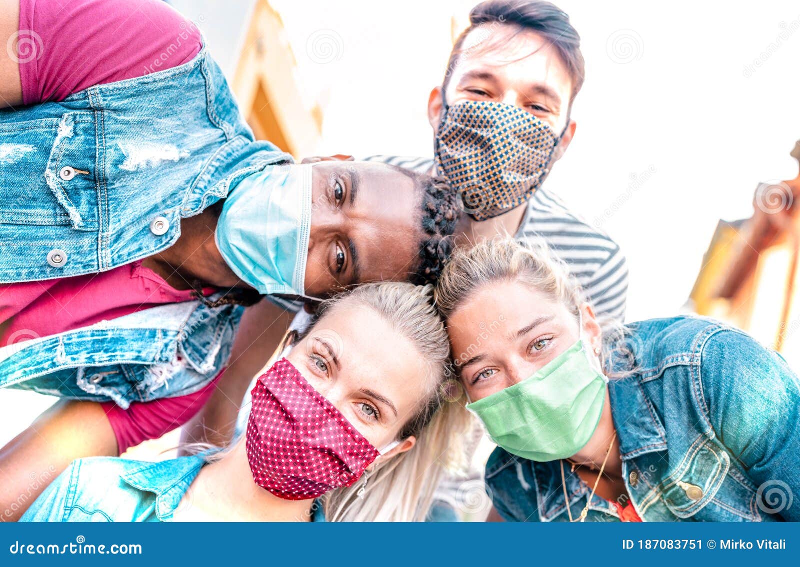 multiracial millenial friends taking selfie smiling behind face masks - happy friendship and new normal concept with young people