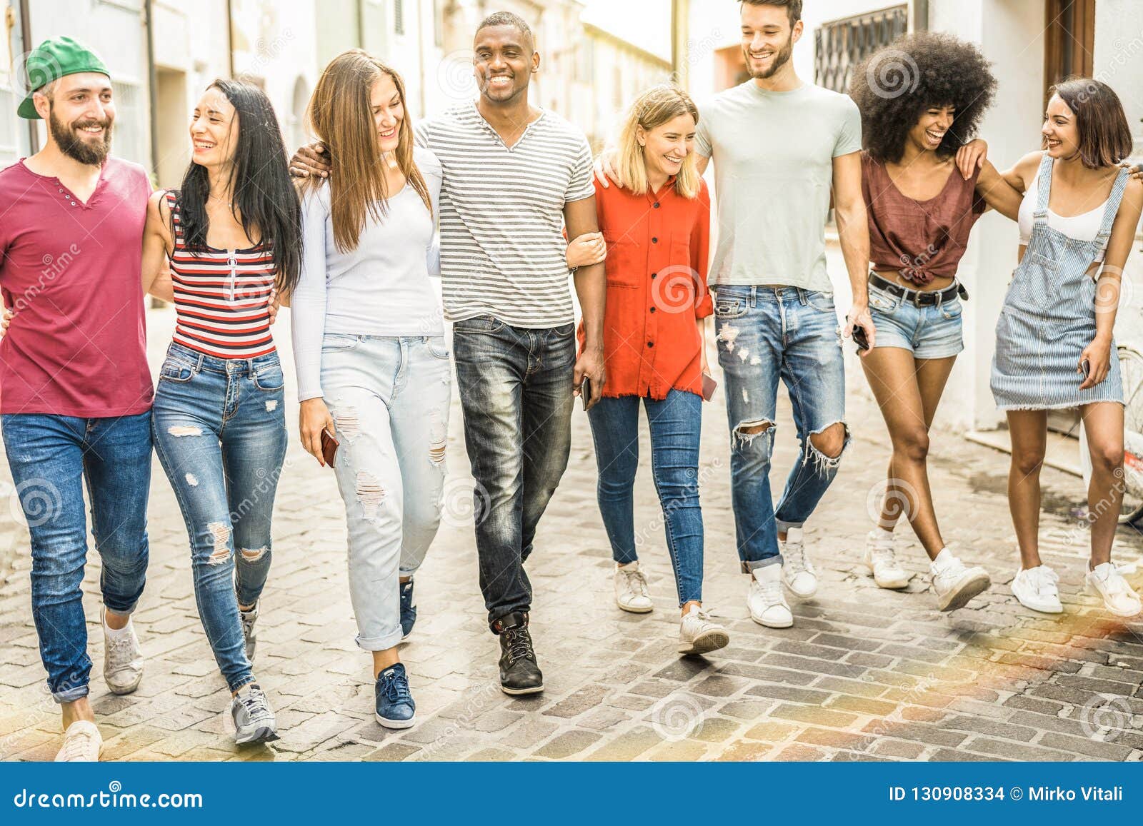 multiracial millennial friends walking and talking in city center