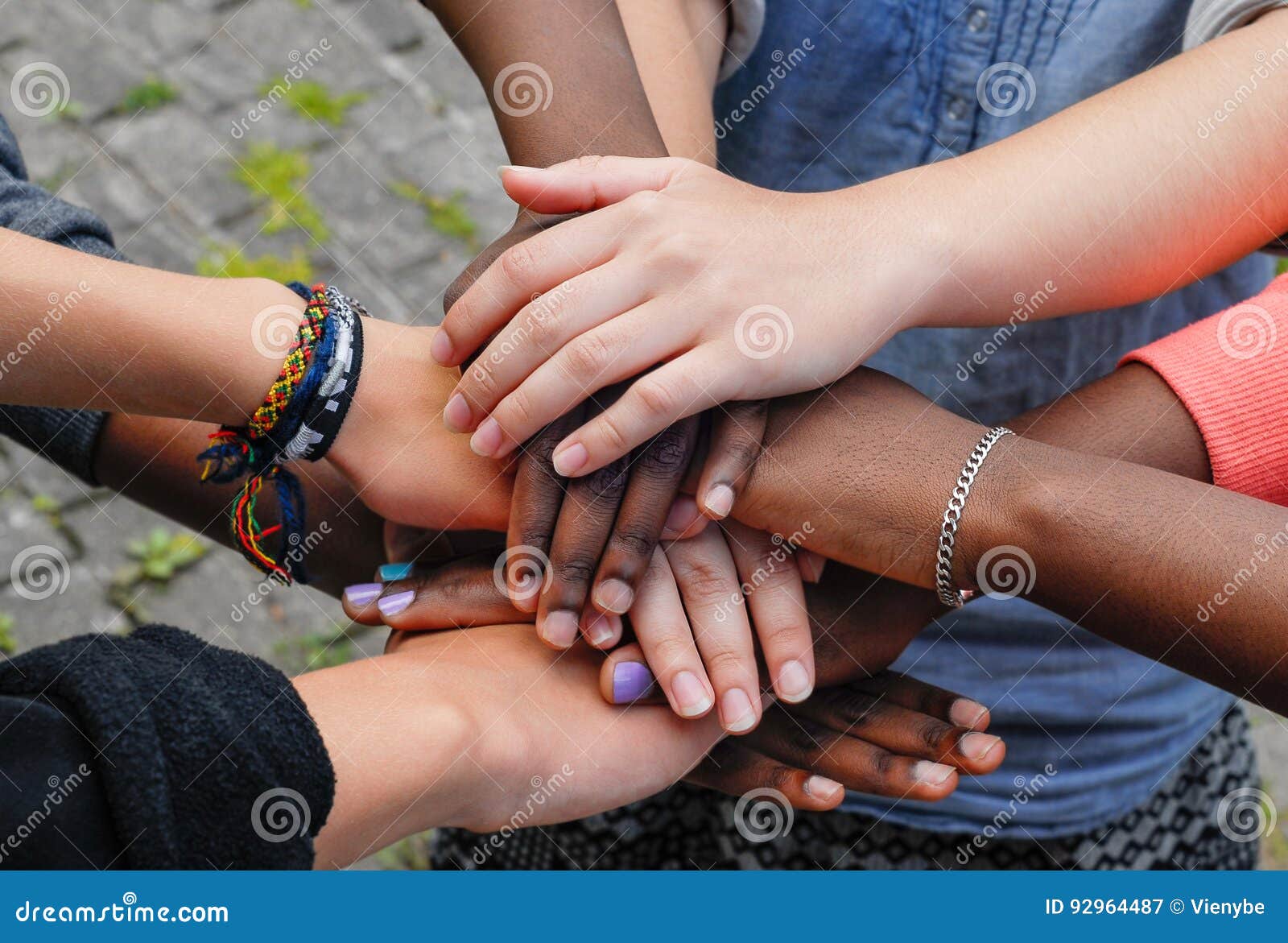 multiracial teen friends joining hands together in cooperation