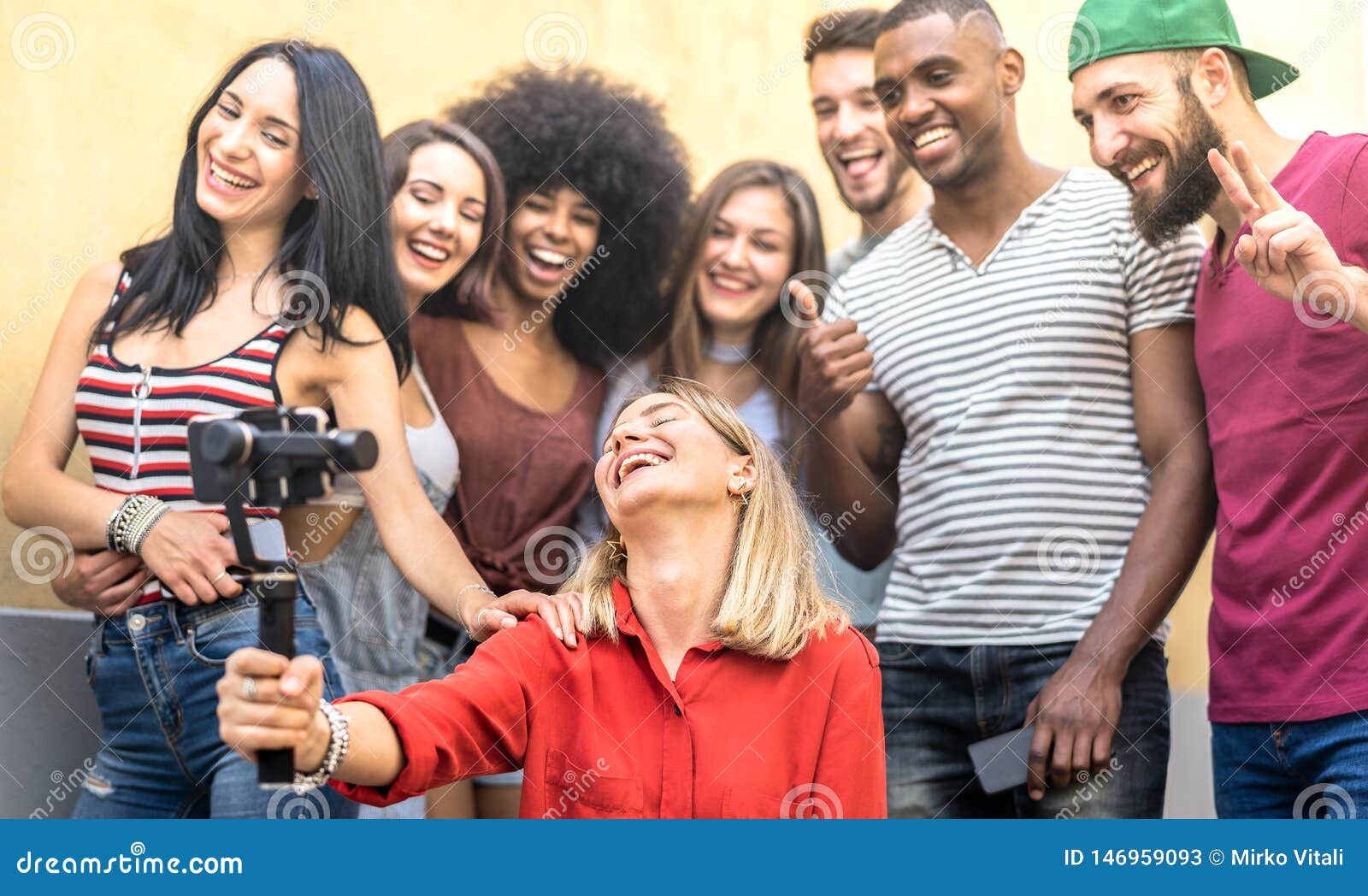 multiracial young friends taking selfie with mobile smart phone and stabilizer gimbal - friendship concept with millenial people