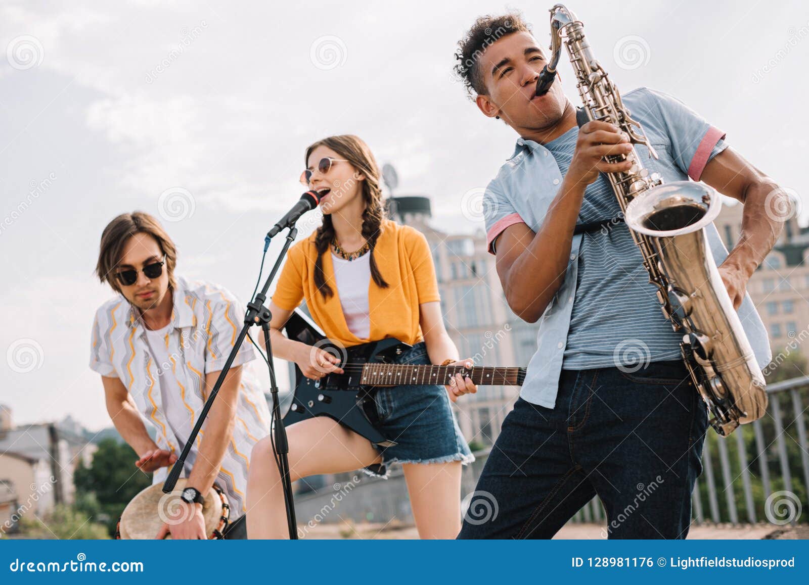 multiracial young people with guitar djembe and saxophone performing