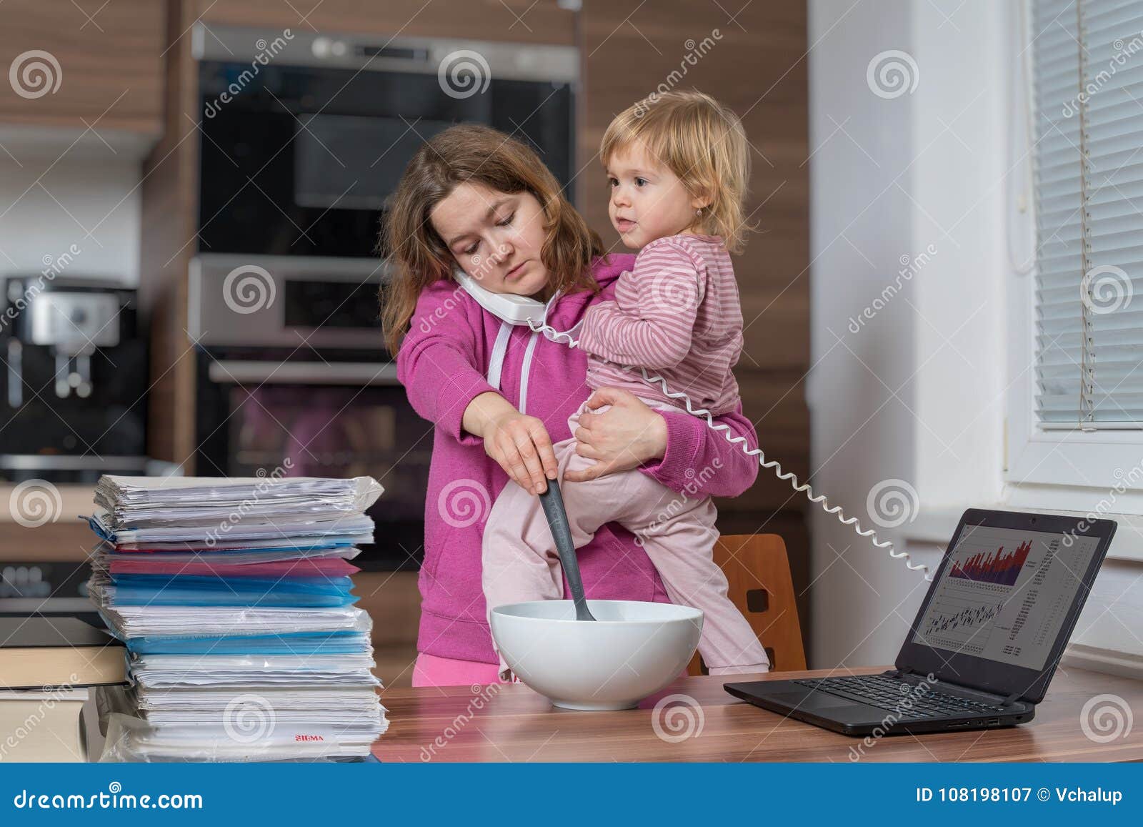 multitasking mother is babysitting and working at home