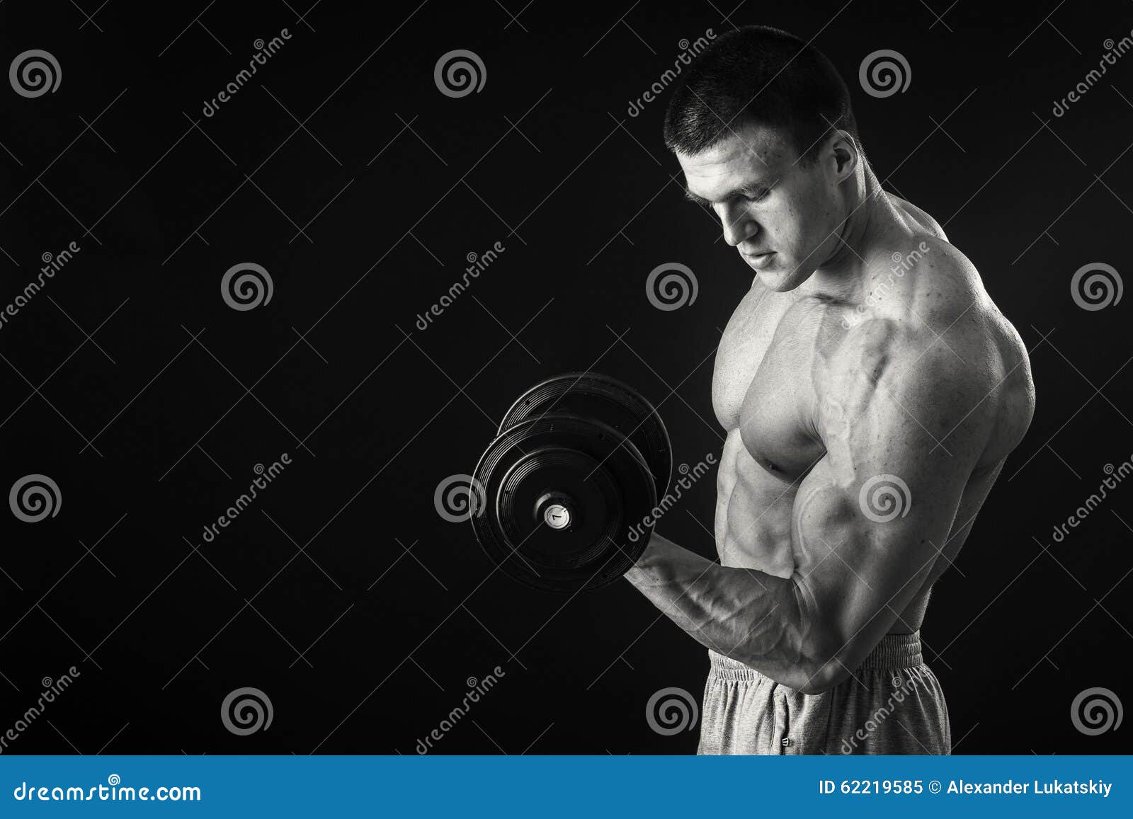 Muscular Athlete Demonstrates His Muscles Under Load on a Dark ...