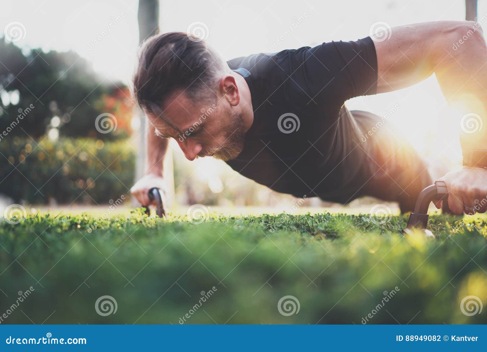 muscular athlete exercising push up outside in sunny park. fit shirtless male fitness model in crossfit exercise